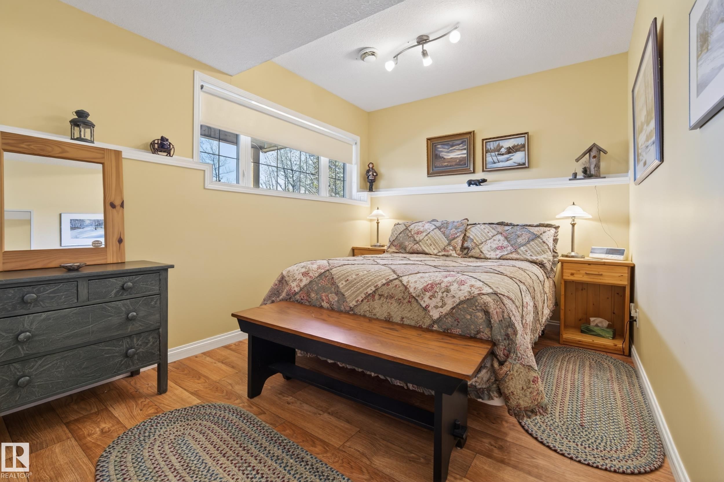 Bedroom with wood-finish flooring, light yellow walls, and a white chair rail - 77 Lakeshore Drive, Rural Leduc County, AB - Indoor Photo Showing Bedroom