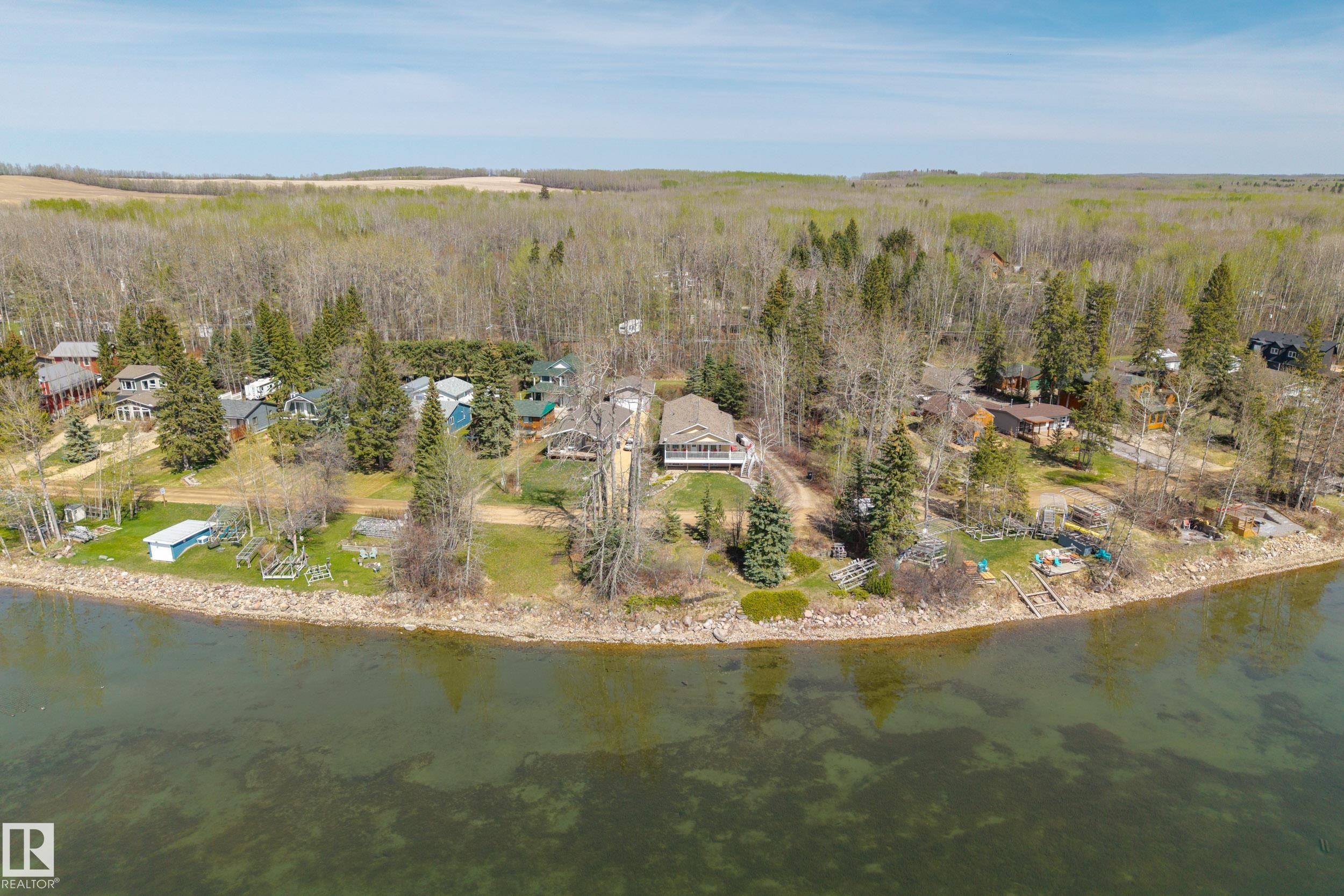 Waterfront property with multiple residential structures, mature trees, and direct water access - 77 Lakeshore Drive, Rural Leduc County, AB - Outdoor With Body Of Water With View