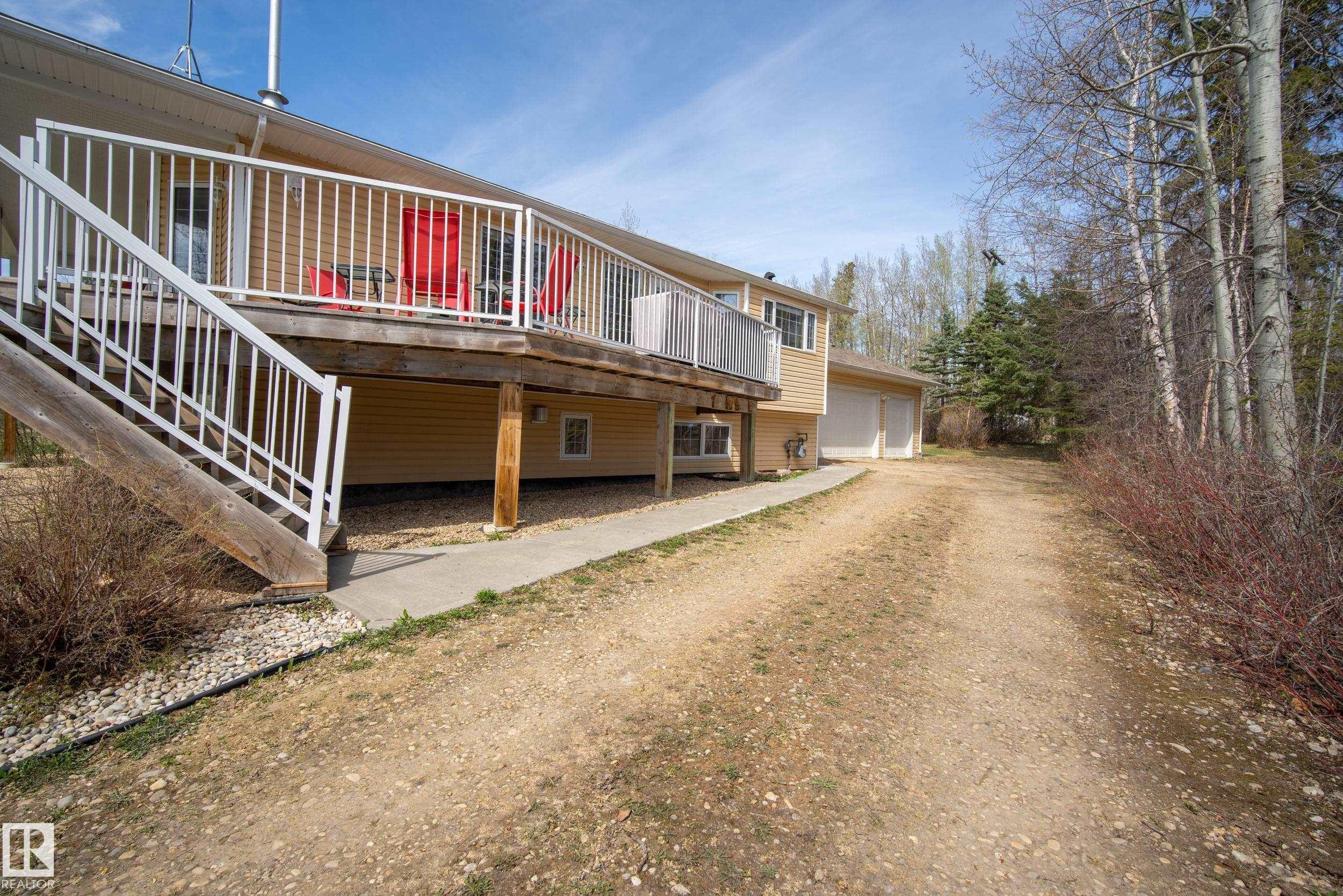 Exterior featuring a beige siding, an elevated wood deck with white railings, and a concrete walkway - 77 Lakeshore Drive, Rural Leduc County, AB - Outdoor
