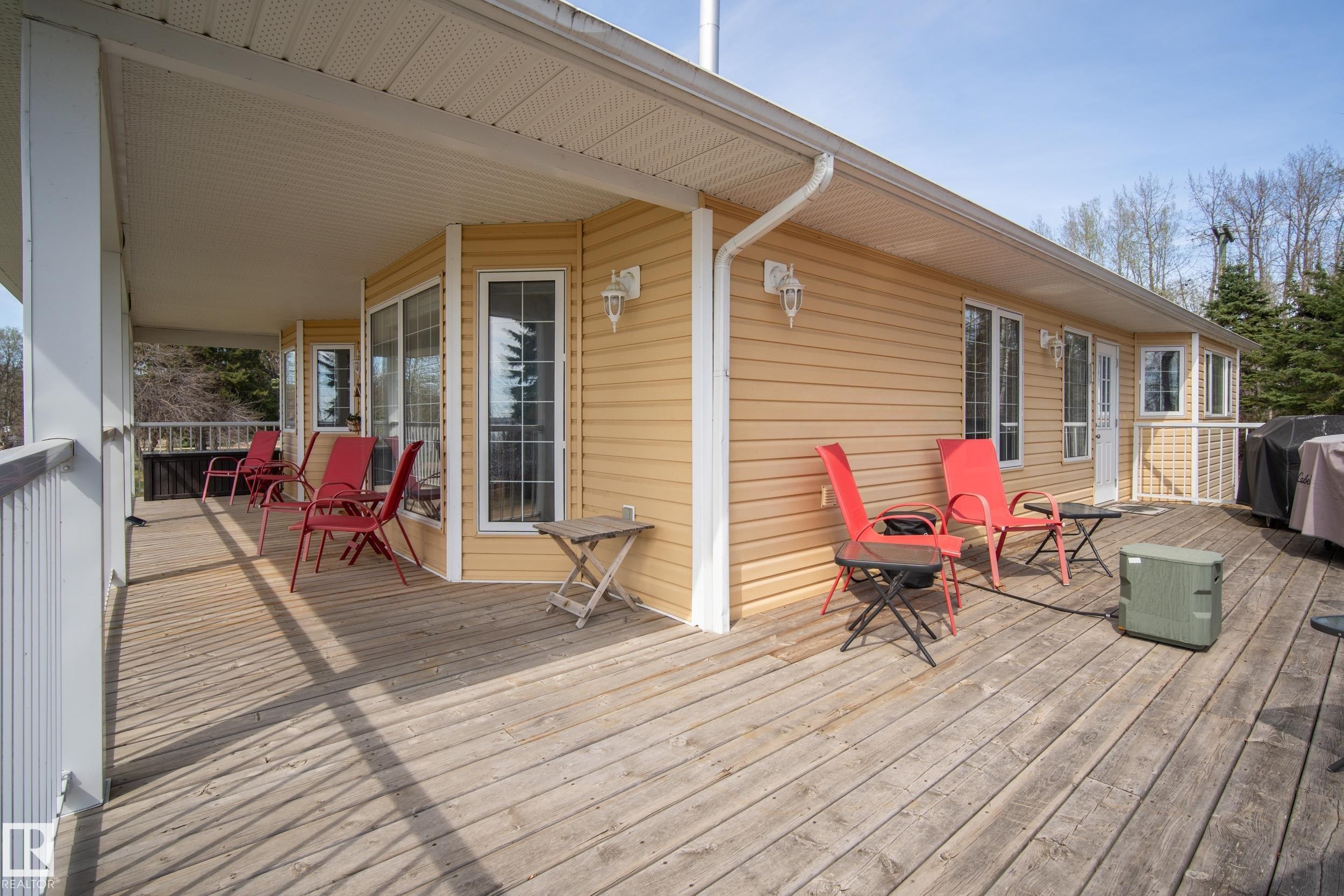 Expansive outdoor decking features a covered porch area with white railings and an exposed sun deck - 77 Lakeshore Drive, Rural Leduc County, AB - Outdoor With Deck Patio Veranda With Exterior