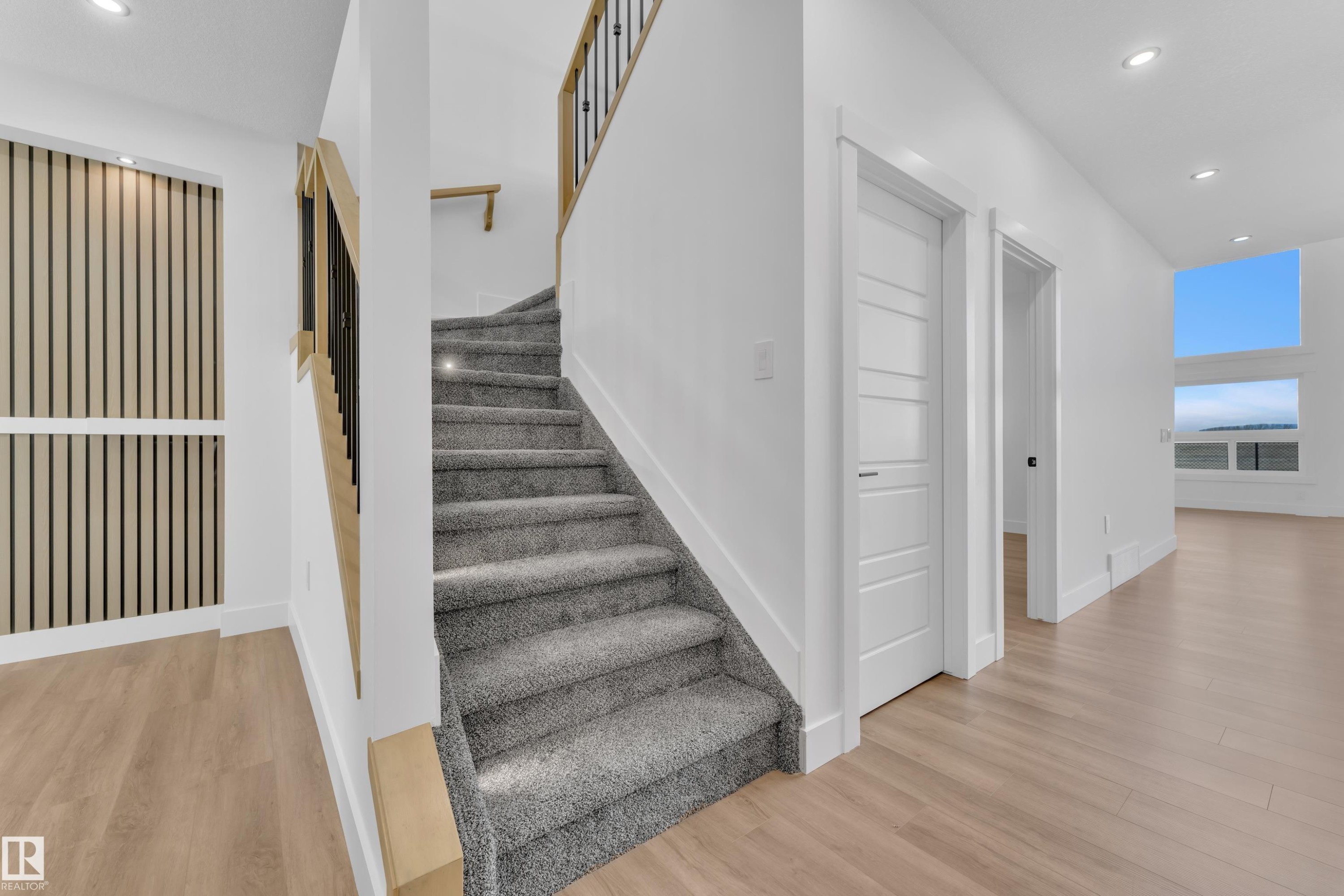Light gray carpeted staircase featuring contemporary black metal and wood railings - 13128 187 Avenue, Edmonton, AB - Indoor Photo Showing Other Room