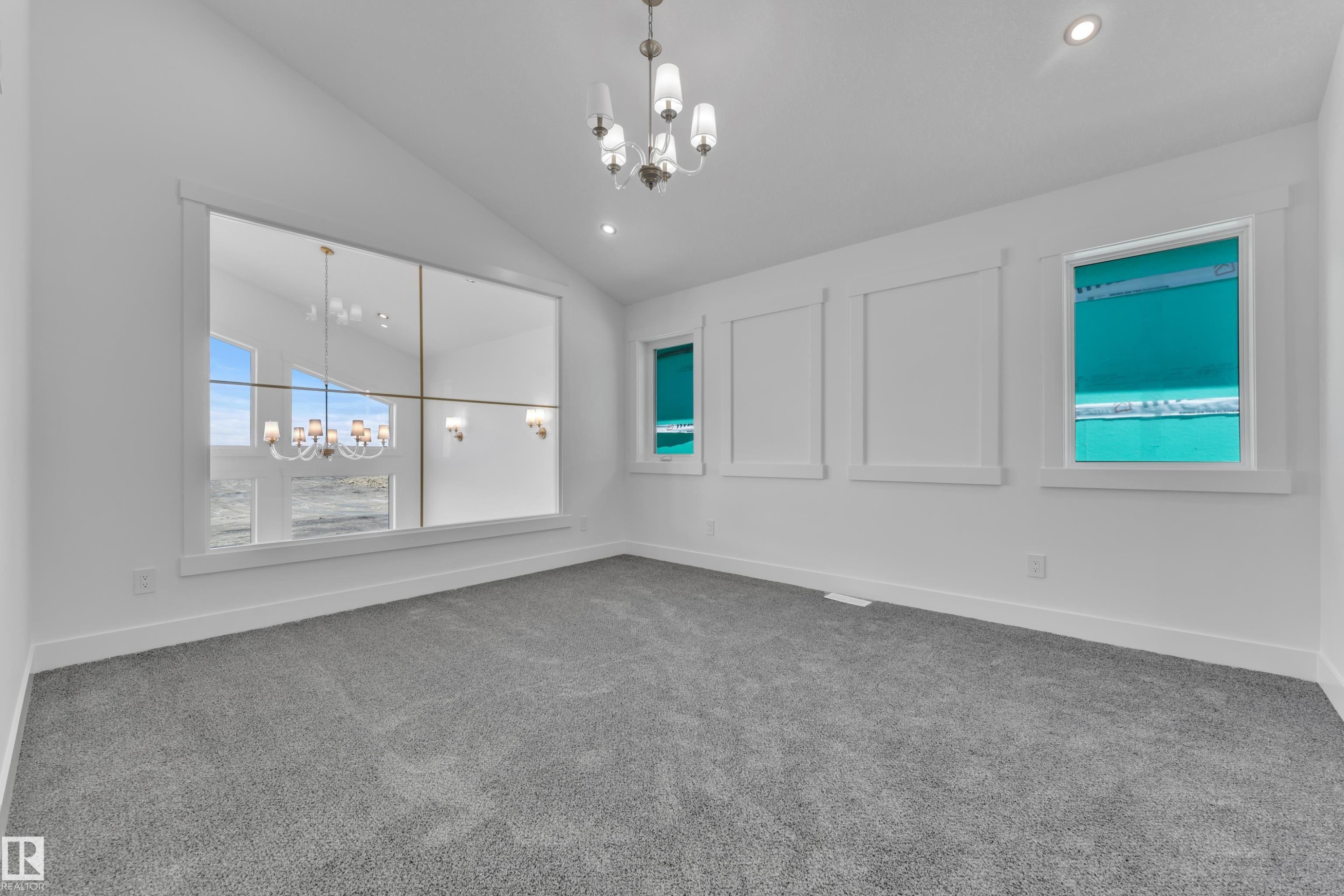 Spacious room featuring vaulted ceilings, a large multi-pane window with a chandelier reflection, recessed lighting, and grey carpet flooring - 13128 187 Avenue, Edmonton, AB - Indoor Photo Showing Other Room