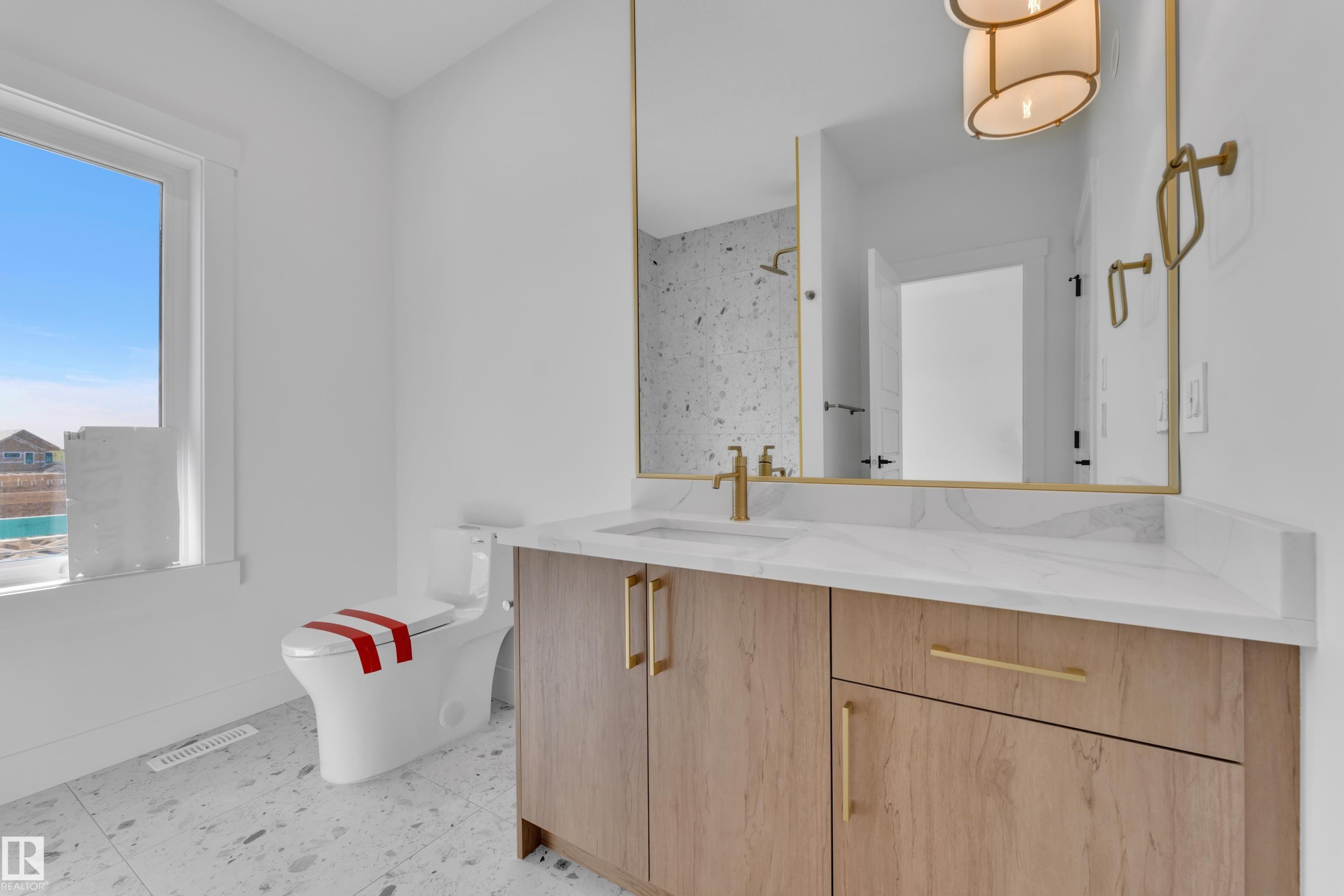 Bathroom featuring a wood-finish vanity with gold-tone hardware, a white countertop, and an integrated sink - 13128 187 Avenue, Edmonton, AB - Indoor Photo Showing Bathroom
