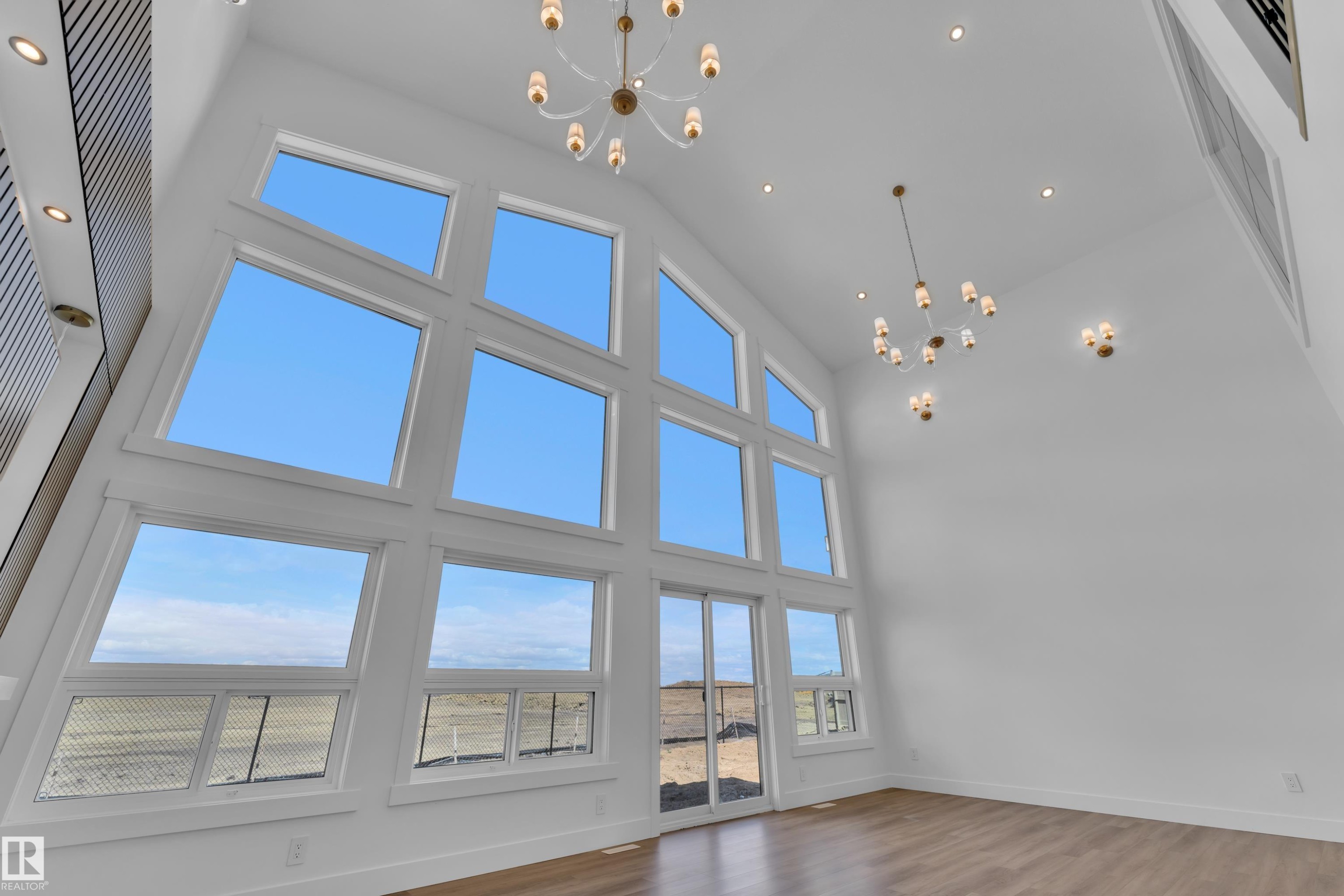 Soaring ceilings complemented by multiple contemporary chandeliers and recessed lighting - 13128 187 Avenue, Edmonton, AB - Indoor Photo Showing Other Room