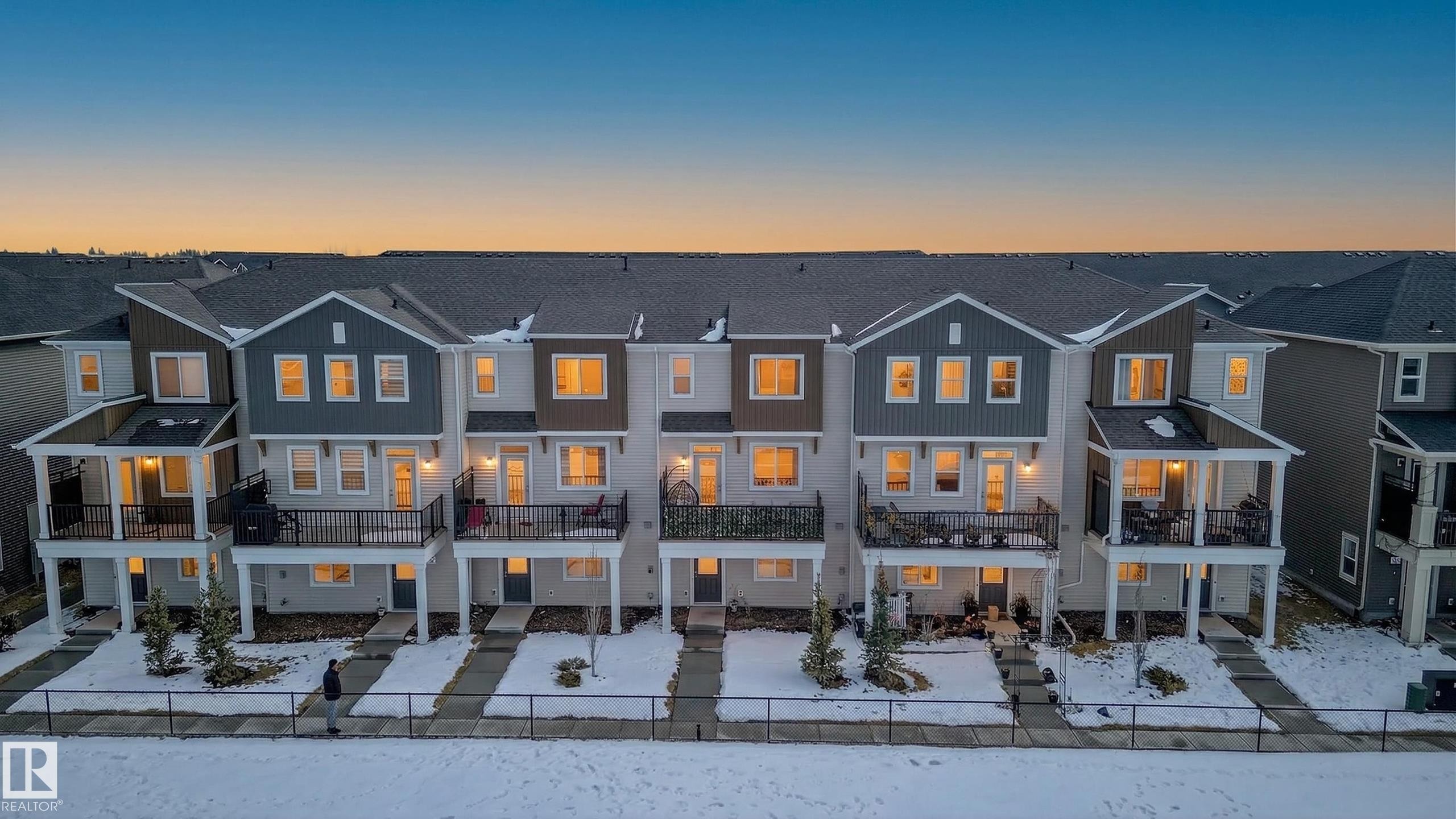 The property features a townhome style with multiple units, each presenting a contemporary exterior design with varying siding colors and a dark gray roof - 15 2072 Wonnacott Way, Edmonton, AB - Outdoor With Facade