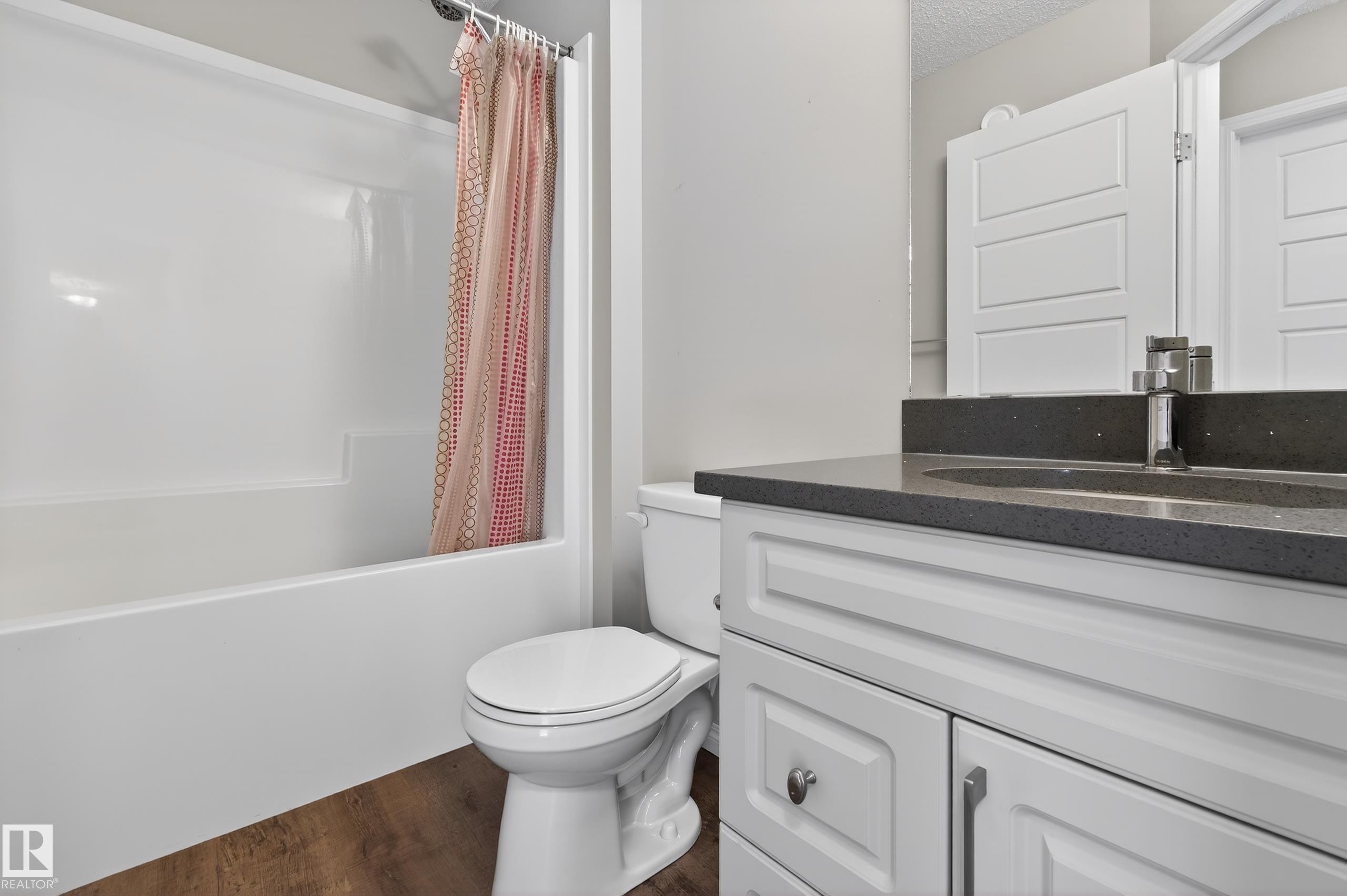 Bathroom featuring a white vanity with a dark countertop, an undermount sink, and a white toilet - 15 2072 Wonnacott Way, Edmonton, AB - Indoor Photo Showing Bathroom