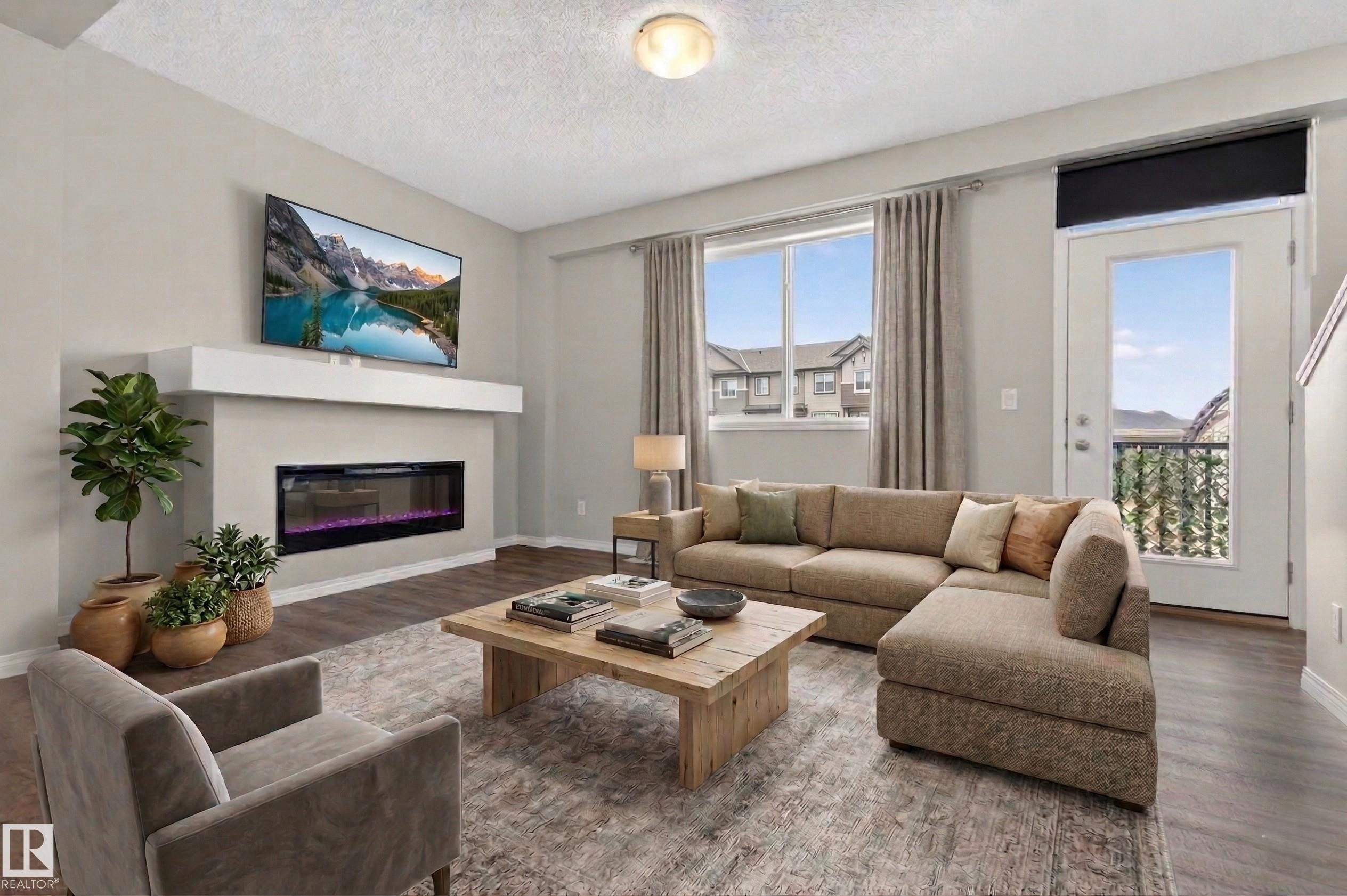 The property features a contemporary living area with a built-in fireplace, hardwood flooring, and a large window providing natural light - 15 2072 Wonnacott Way, Edmonton, AB - Indoor Photo Showing Living Room With Fireplace