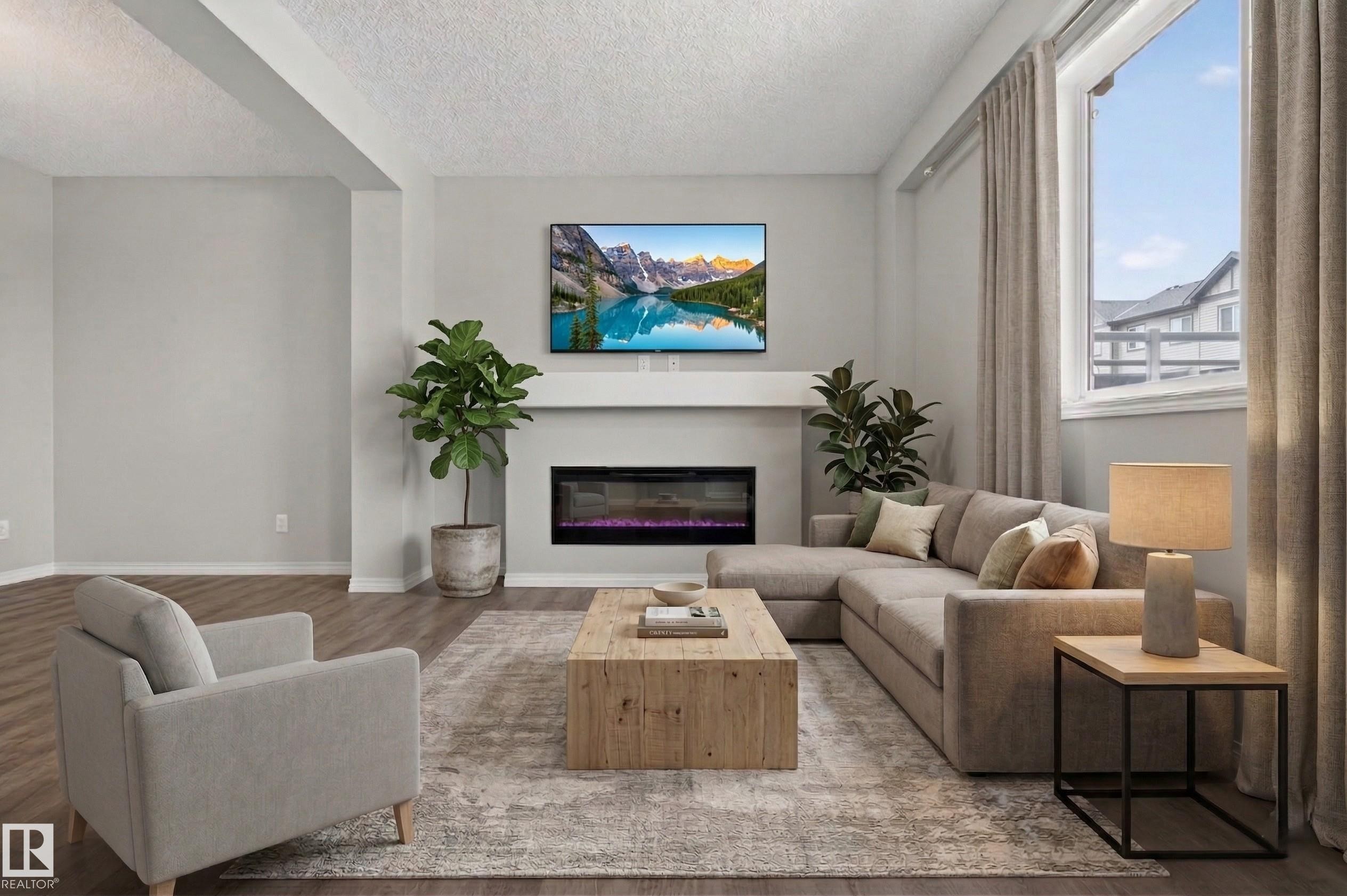 This inviting living area features light-colored walls, wood-look flooring, and a large window with drapes - 15 2072 Wonnacott Way, Edmonton, AB - Indoor Photo Showing Living Room With Fireplace
