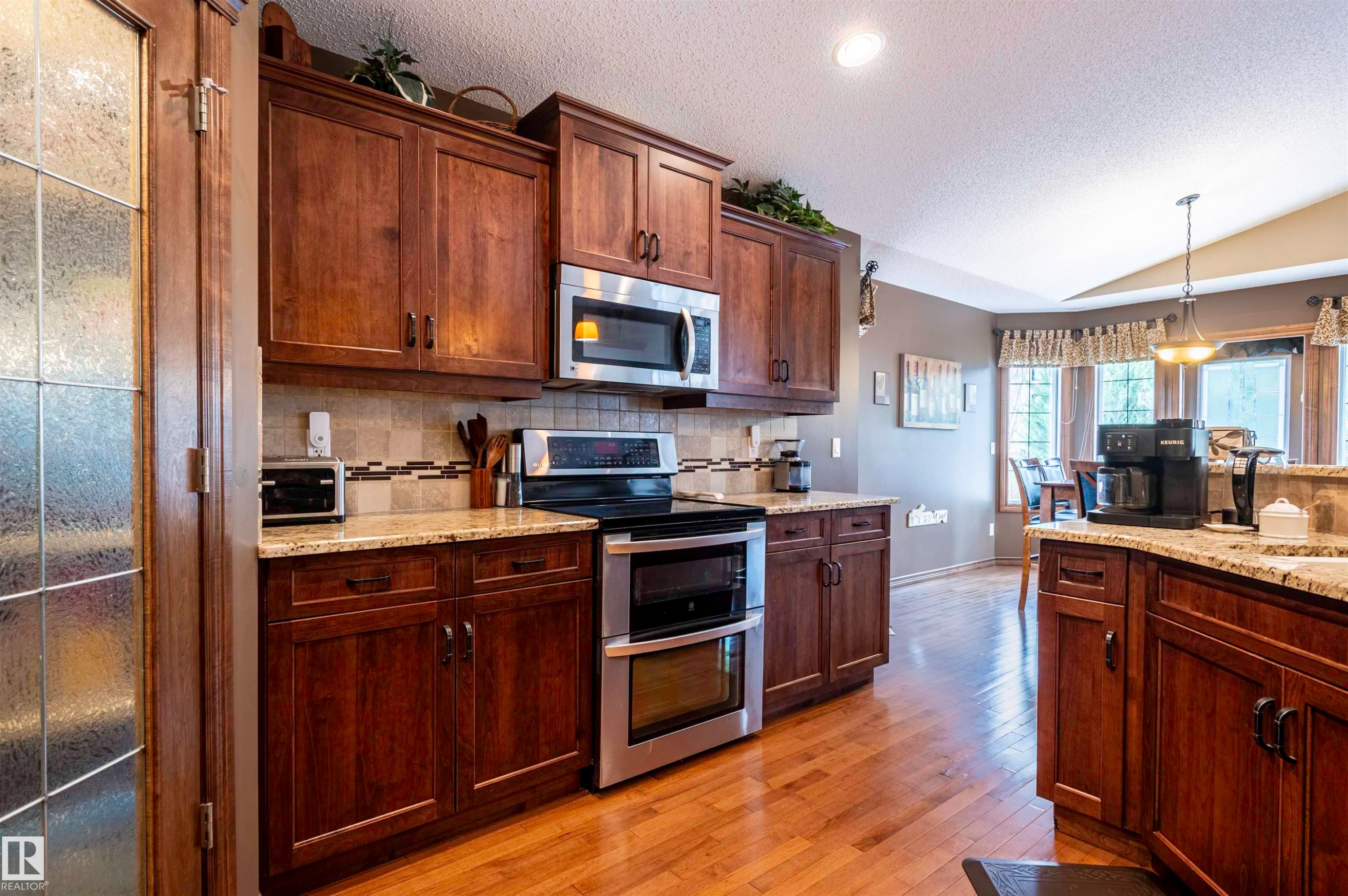 Kitchen featuring extensive wood cabinetry, granite countertops, stainless steel appliances, and wood-finish flooring - 19 Newton Place, St. Albert, AB - Indoor Photo Showing Kitchen