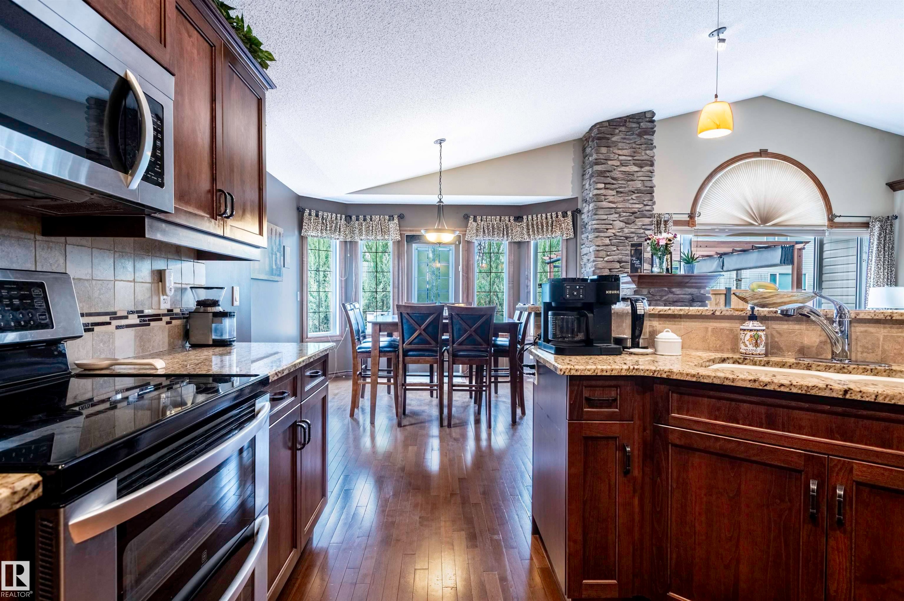 Kitchen featuring wood-finish flooring, dark wood cabinetry, and a stone-clad architectural element - 19 Newton Place, St. Albert, AB - Indoor Photo Showing Kitchen