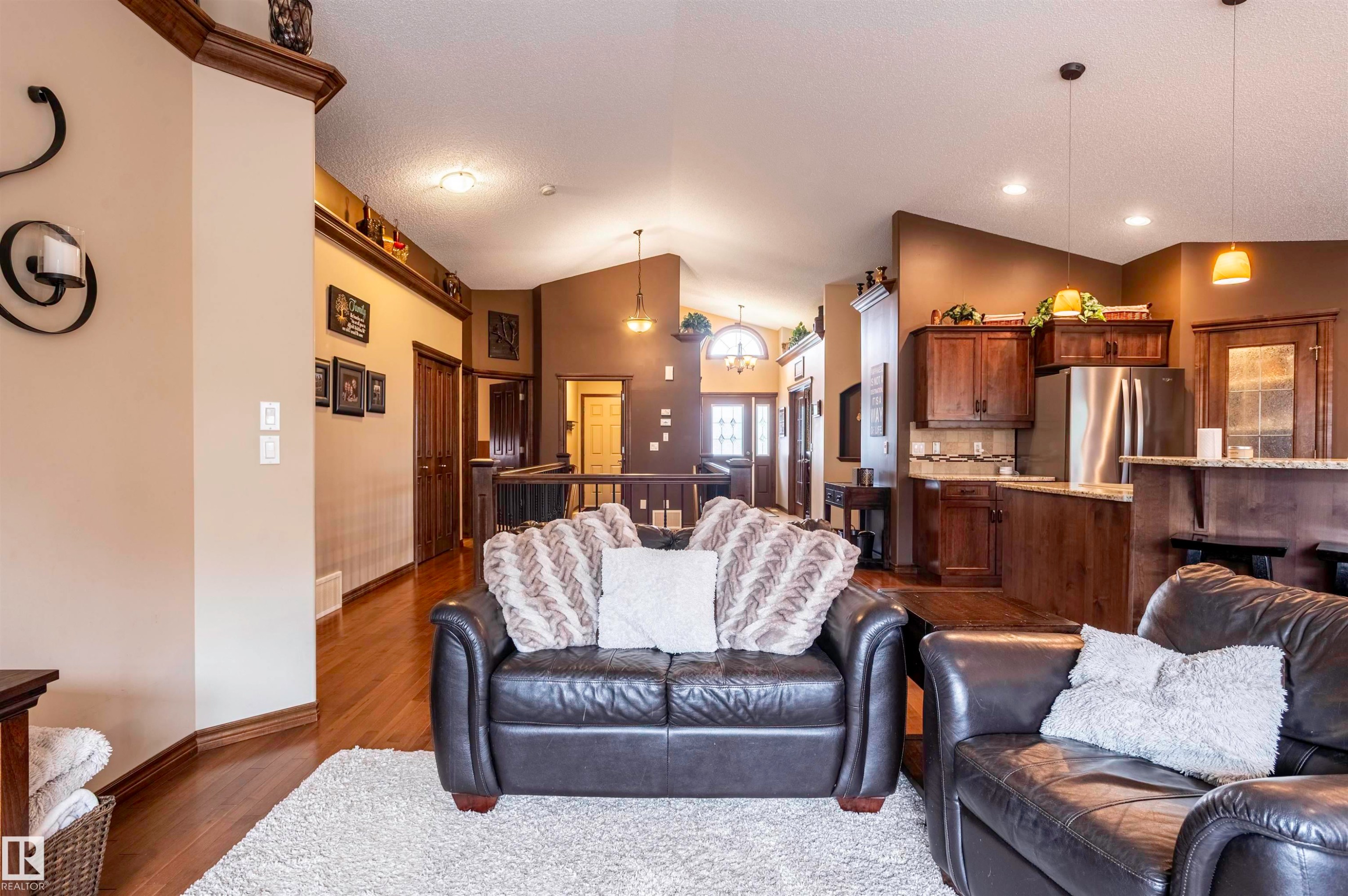 Open concept interior featuring wood-finish flooring, recessed lighting, a kitchen with wood cabinetry and stainless steel appliances, and a breakfast bar - 19 Newton Place, St. Albert, AB - Indoor Photo Showing Living Room