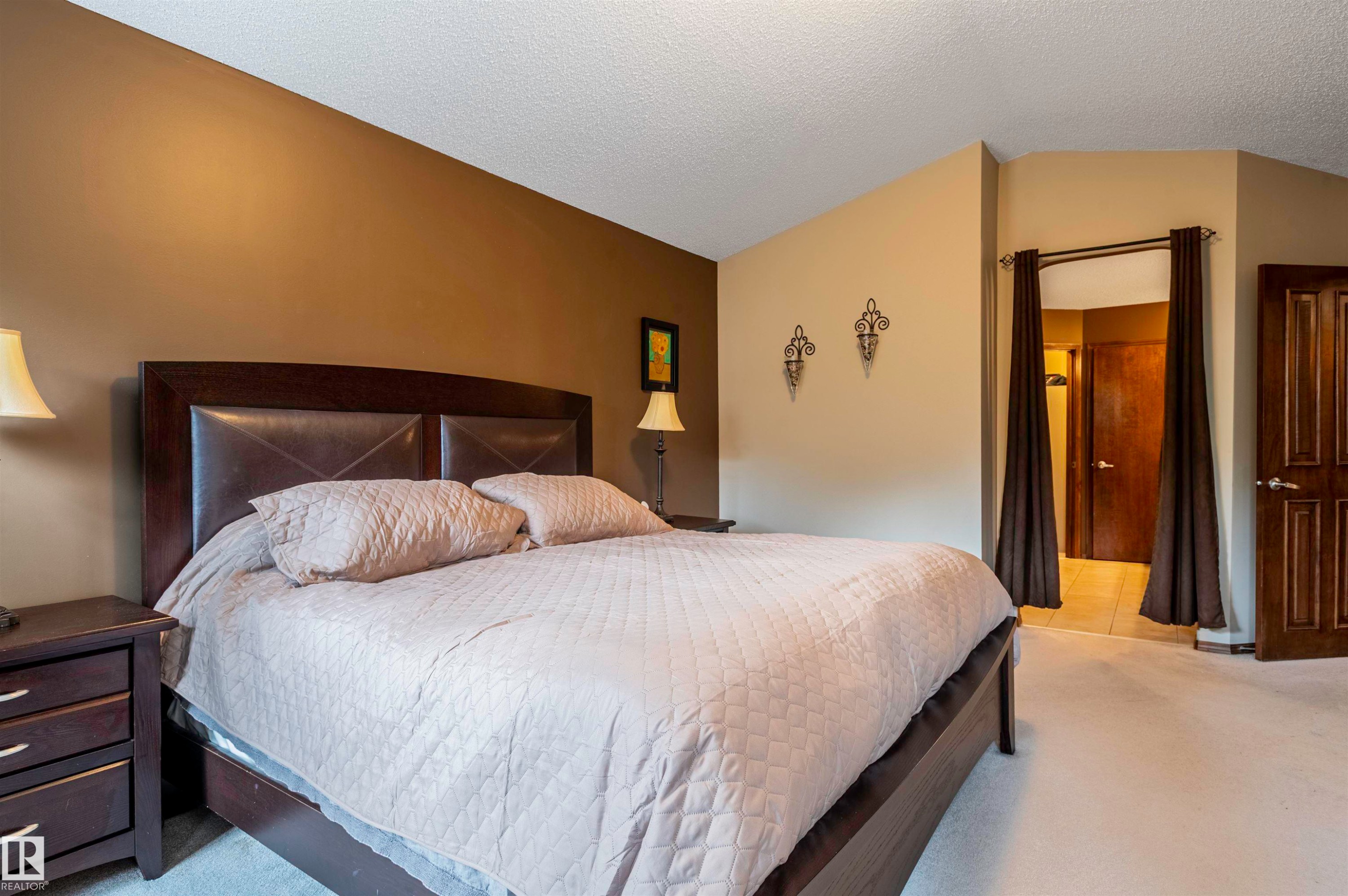 Spacious bedroom with vaulted ceiling, carpet flooring, and a warm two-tone paint scheme - 19 Newton Place, St. Albert, AB - Indoor Photo Showing Bedroom