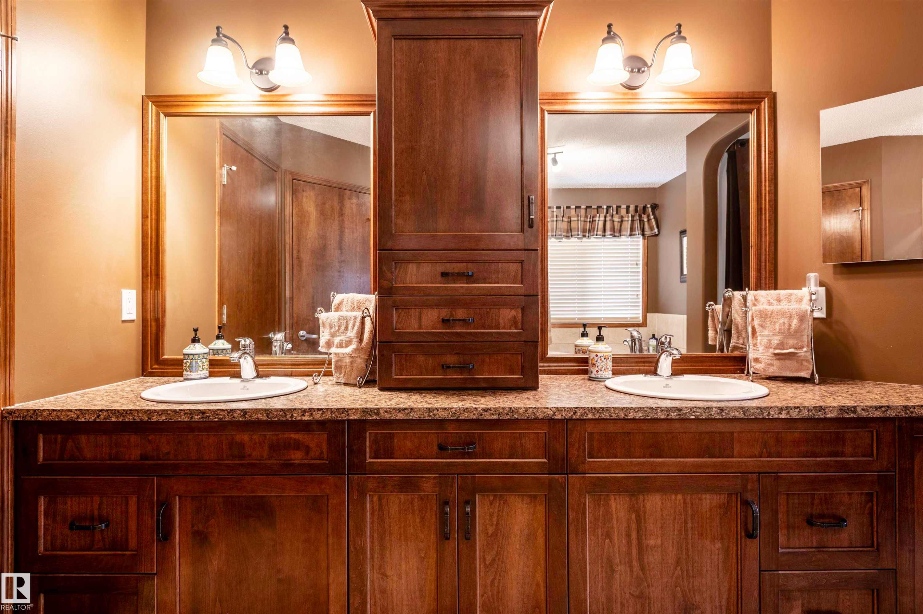 Dual vanity featuring wood-finish cabinetry, integrated sinks, and a stone-look countertop - 19 Newton Place, St. Albert, AB - Indoor Photo Showing Bathroom