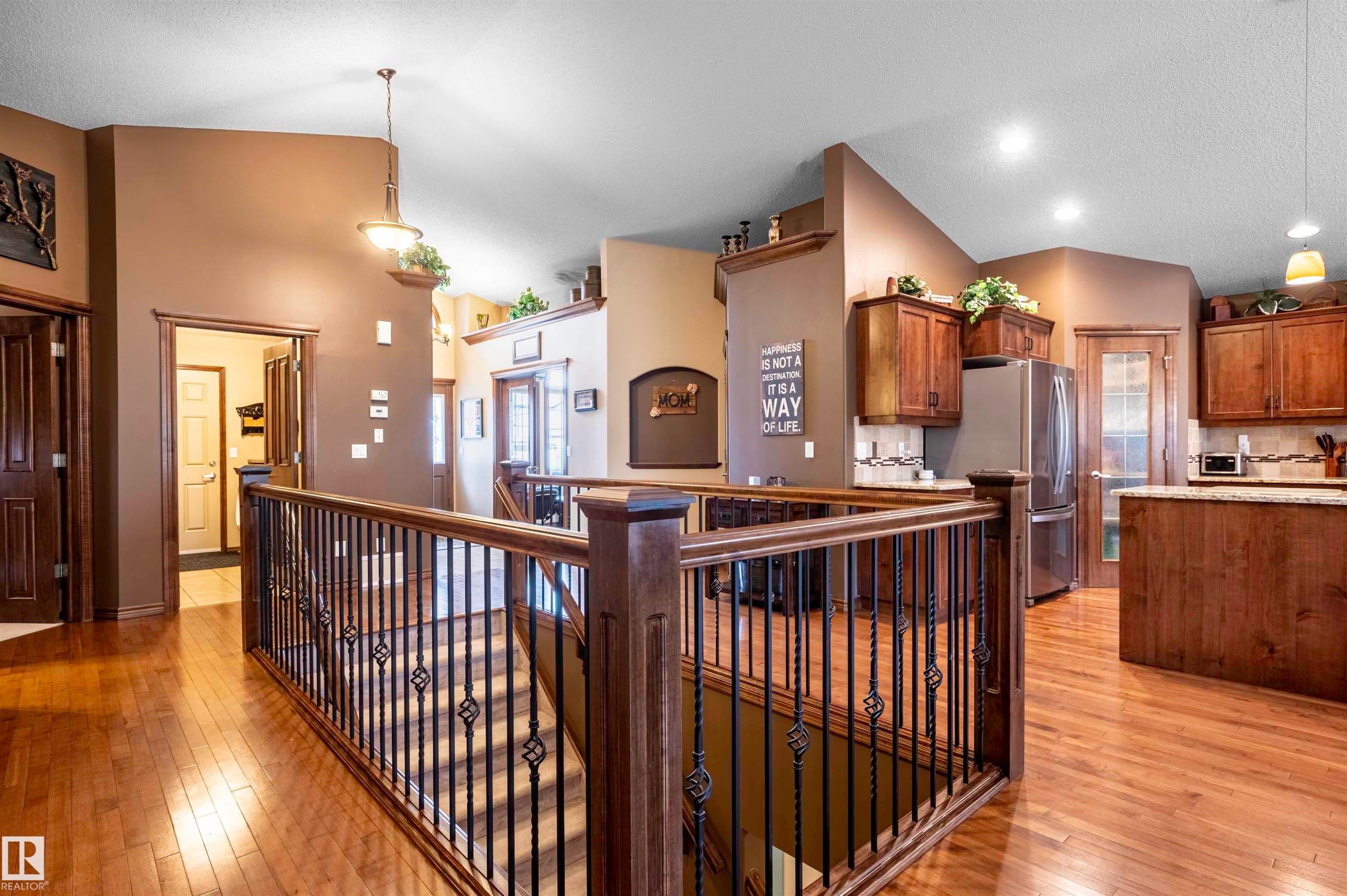 Hardwood flooring and custom wood railing with decorative iron spindles define this interior space - 19 Newton Place, St. Albert, AB - Indoor Photo Showing Other Room