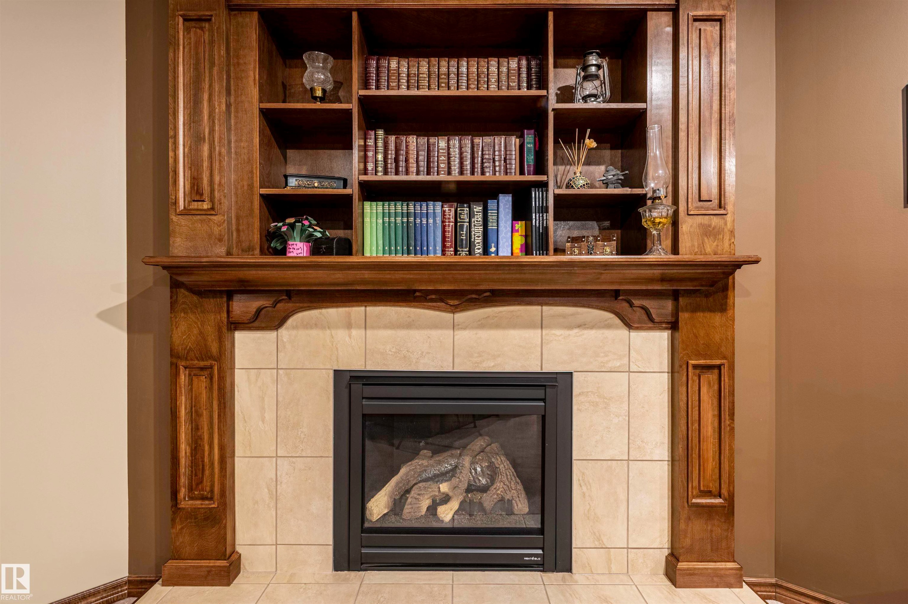 Built-in fireplace with a tiled surround, a dark wood mantel, and integrated wood shelving - 19 Newton Place, St. Albert, AB - Indoor Photo Showing Living Room With Fireplace