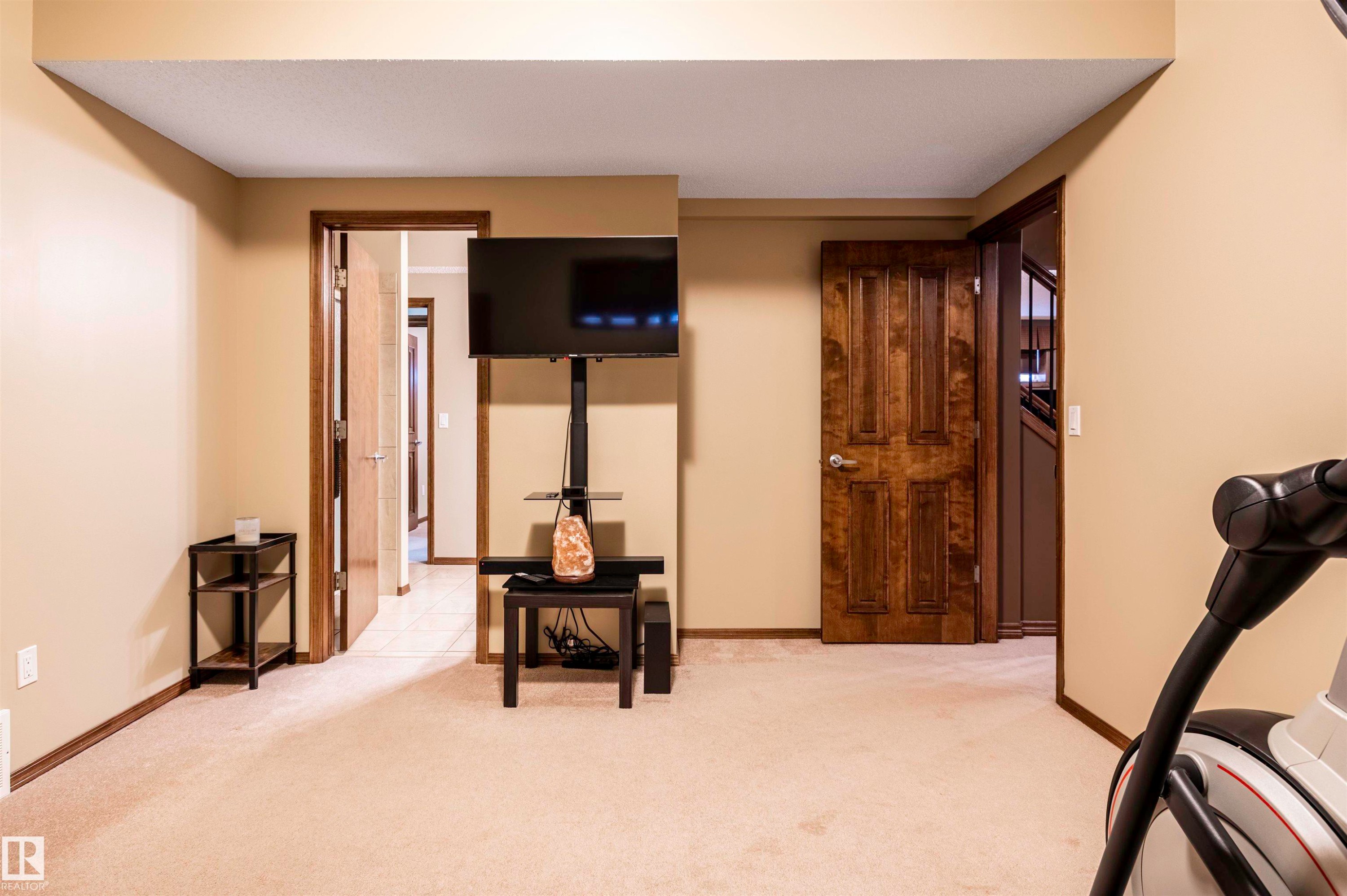 Carpeted room featuring multiple doorways with dark wood-finish trim, beige wall paint, and recessed ceiling details - 19 Newton Place, St. Albert, AB - Indoor