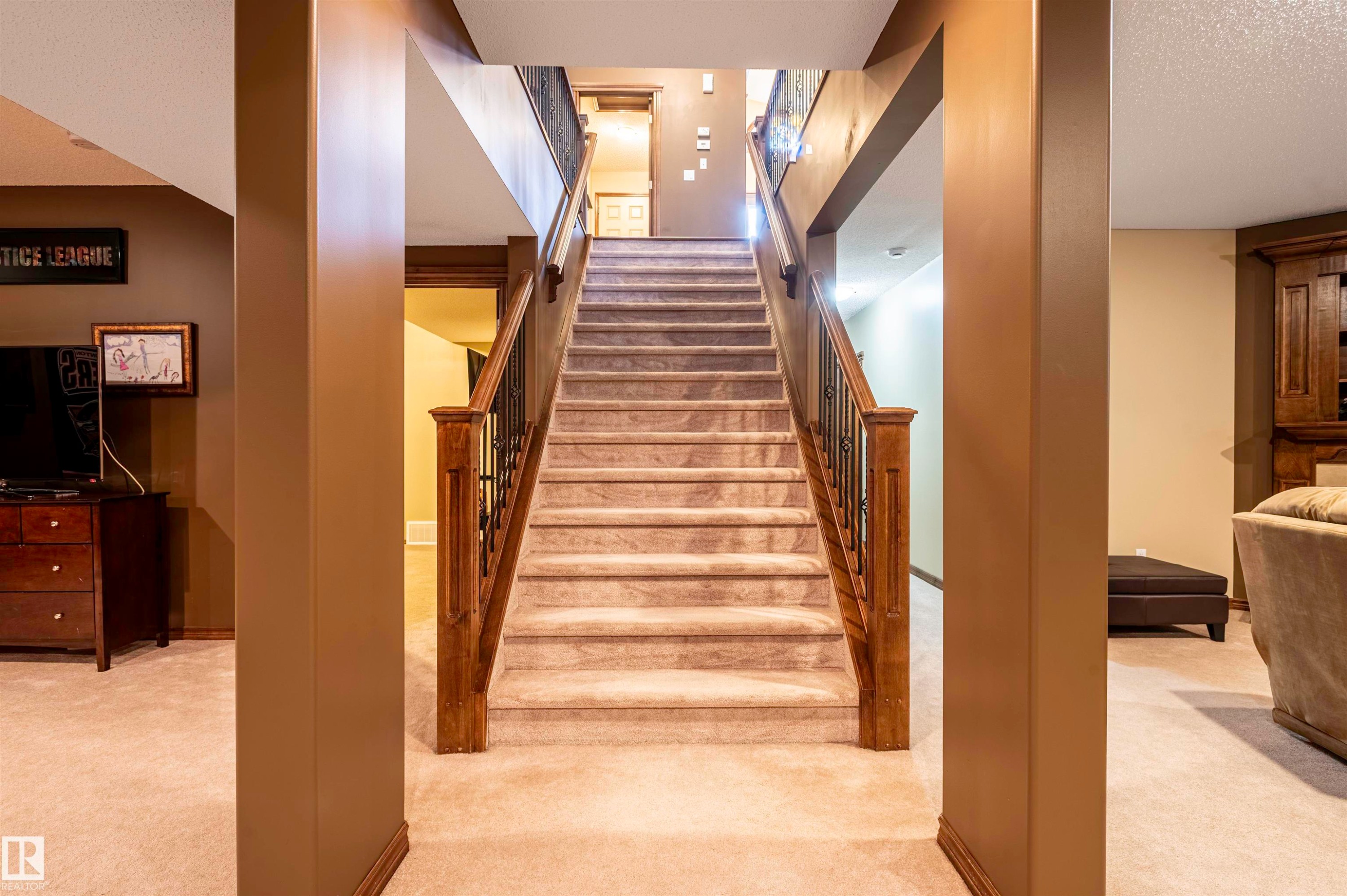 Carpeted staircase with wood newel posts and wrought iron balusters - 19 Newton Place, St. Albert, AB - Indoor Photo Showing Other Room