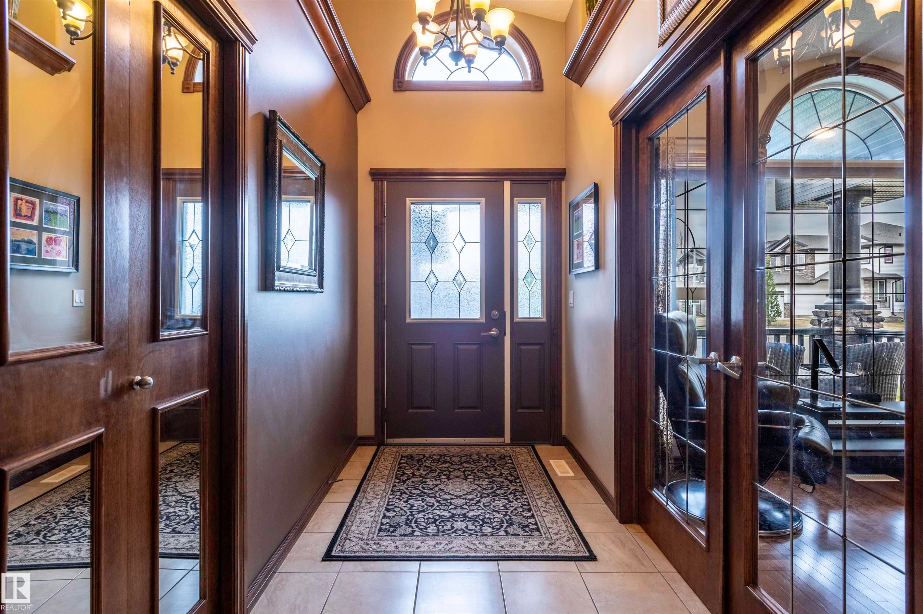 Foyer featuring tile flooring, leaded glass entry door with sidelights, arched transom window, and dark wood trim - 19 Newton Place, St. Albert, AB - Indoor Photo Showing Other Room