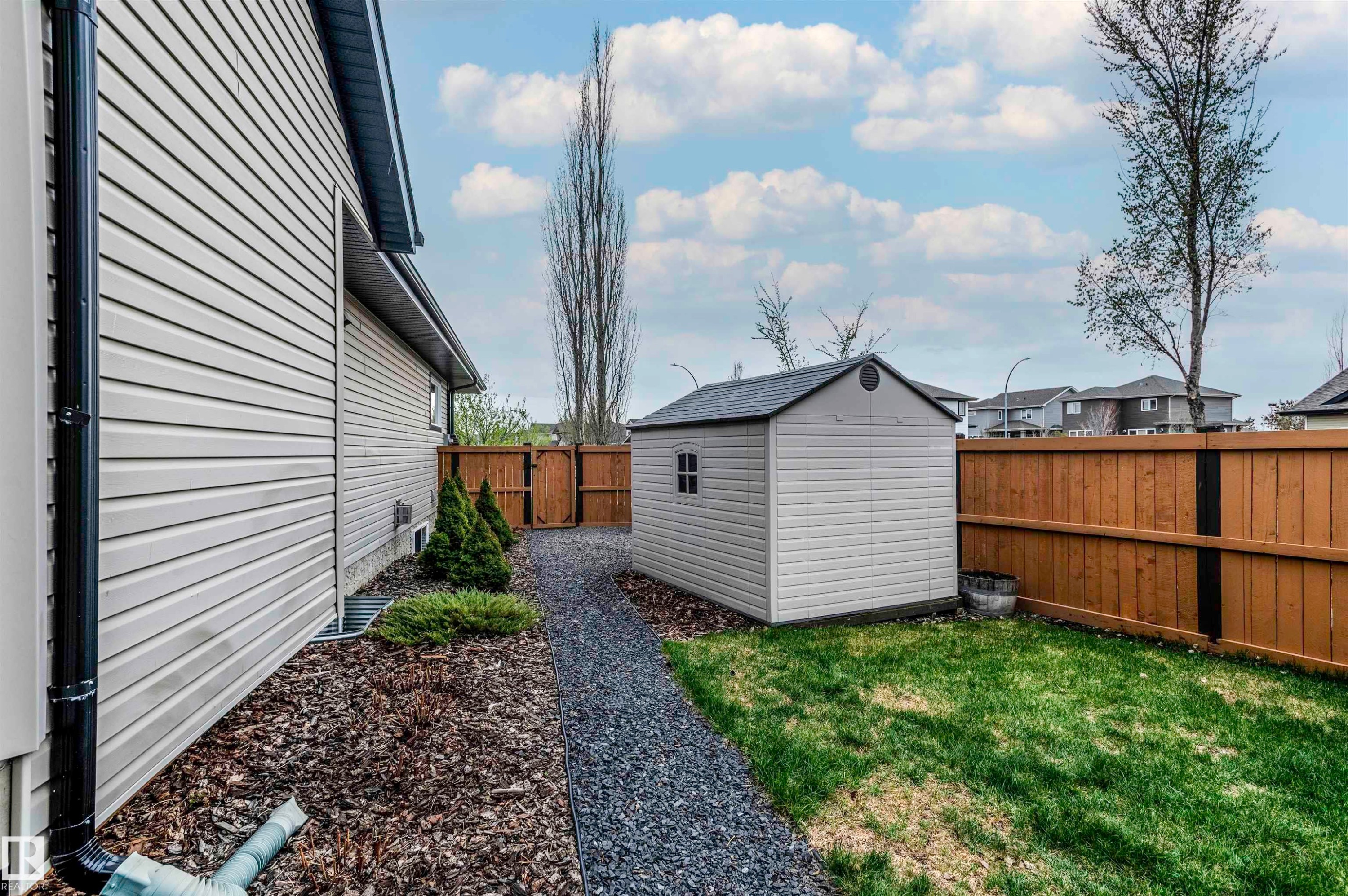 Side yard featuring a gravel path, wood chip landscaping, and a compact storage shed - 19 Newton Place, St. Albert, AB - Outdoor