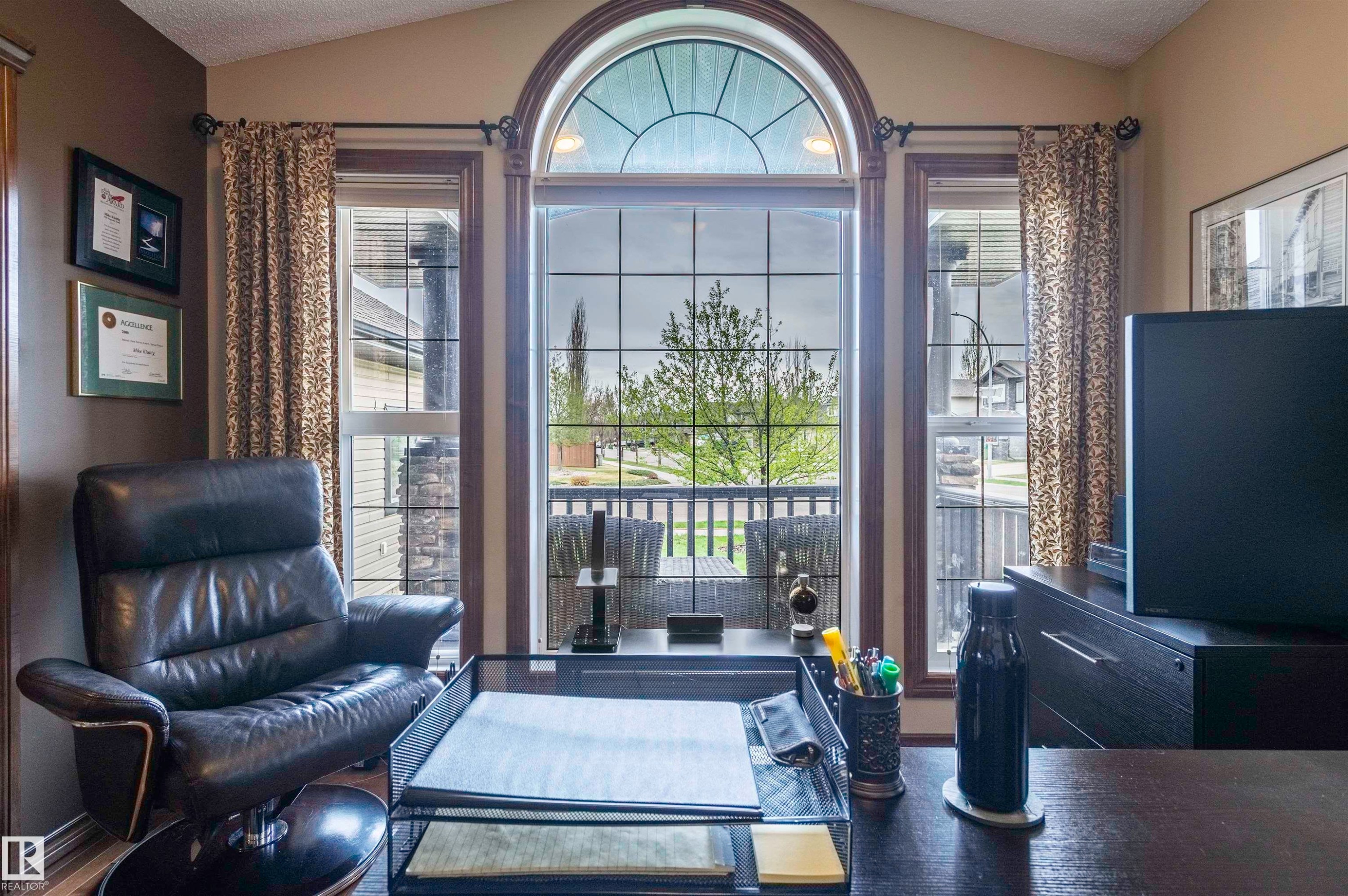 Arch-top window with decorative mullions and side windows, wood-finish flooring, recessed lighting, and wall-mounted shelving - 19 Newton Place, St. Albert, AB - Indoor