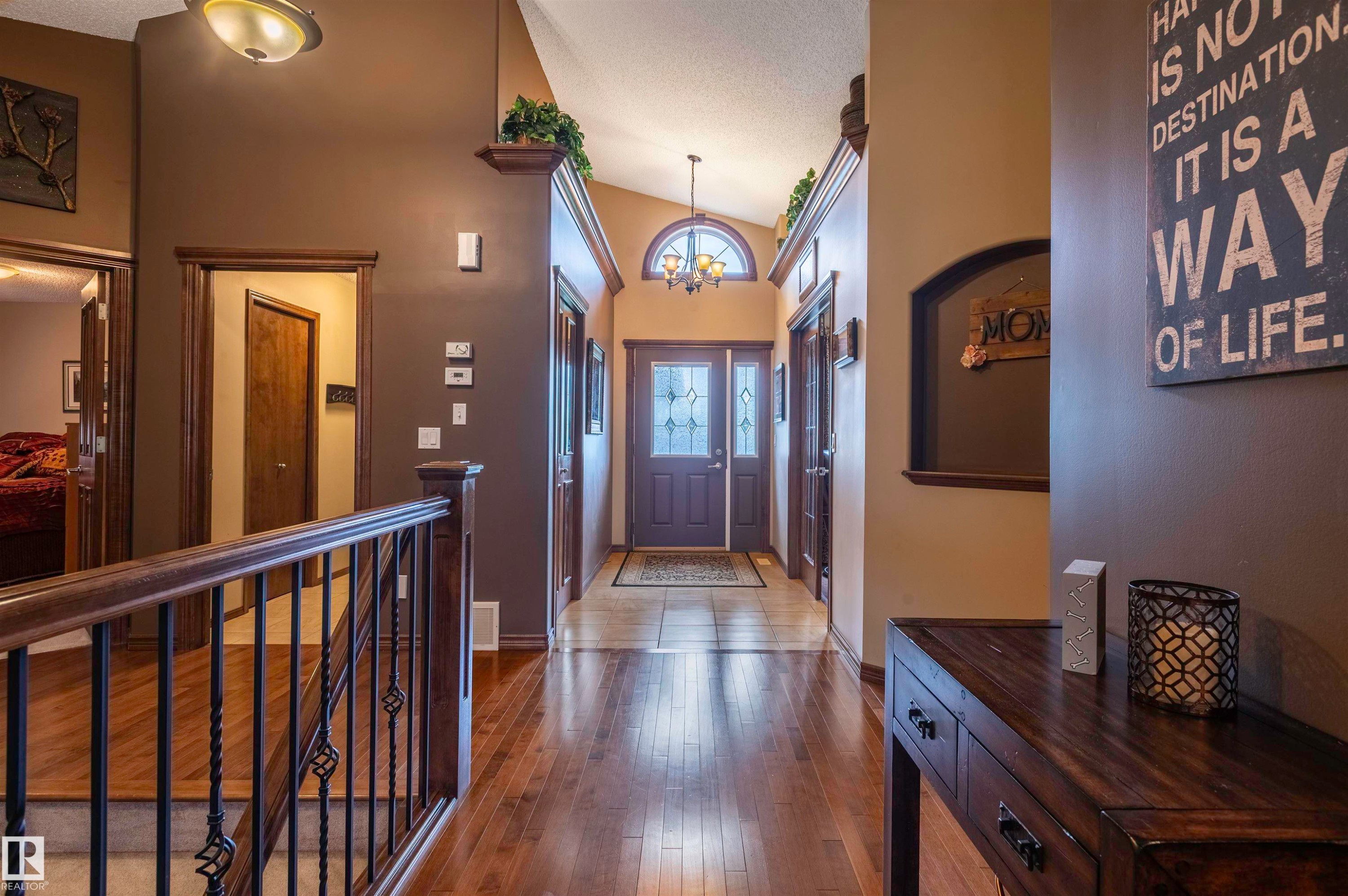 Entryway with wood-finish flooring, a decorative front door with side lights, and an arched transom window - 19 Newton Place, St. Albert, AB - Indoor Photo Showing Other Room