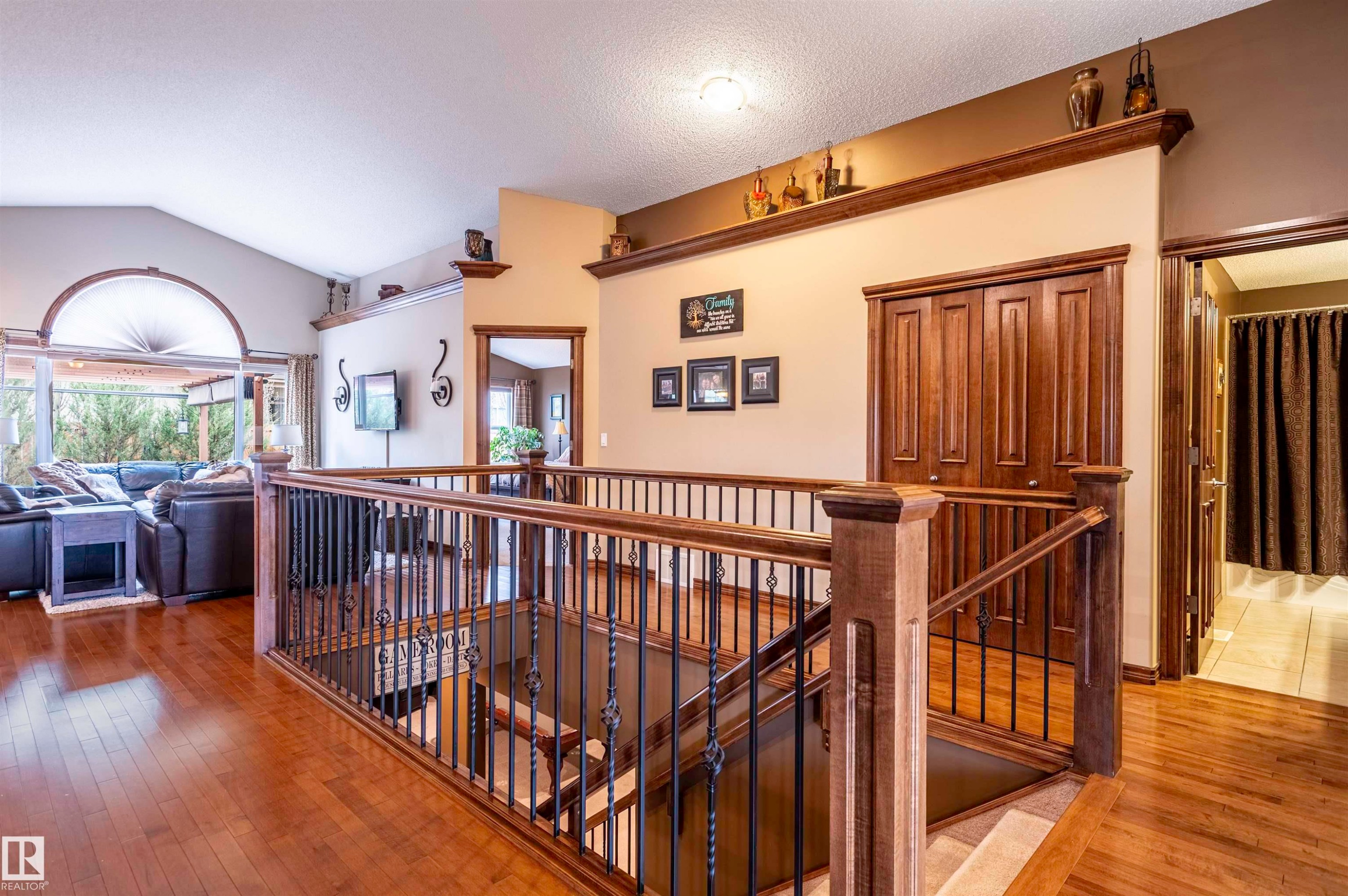 Open landing featuring wood-finish flooring, a wood and wrought-iron staircase, vaulted ceilings, and a large arched window - 19 Newton Place, St. Albert, AB - Indoor Photo Showing Other Room