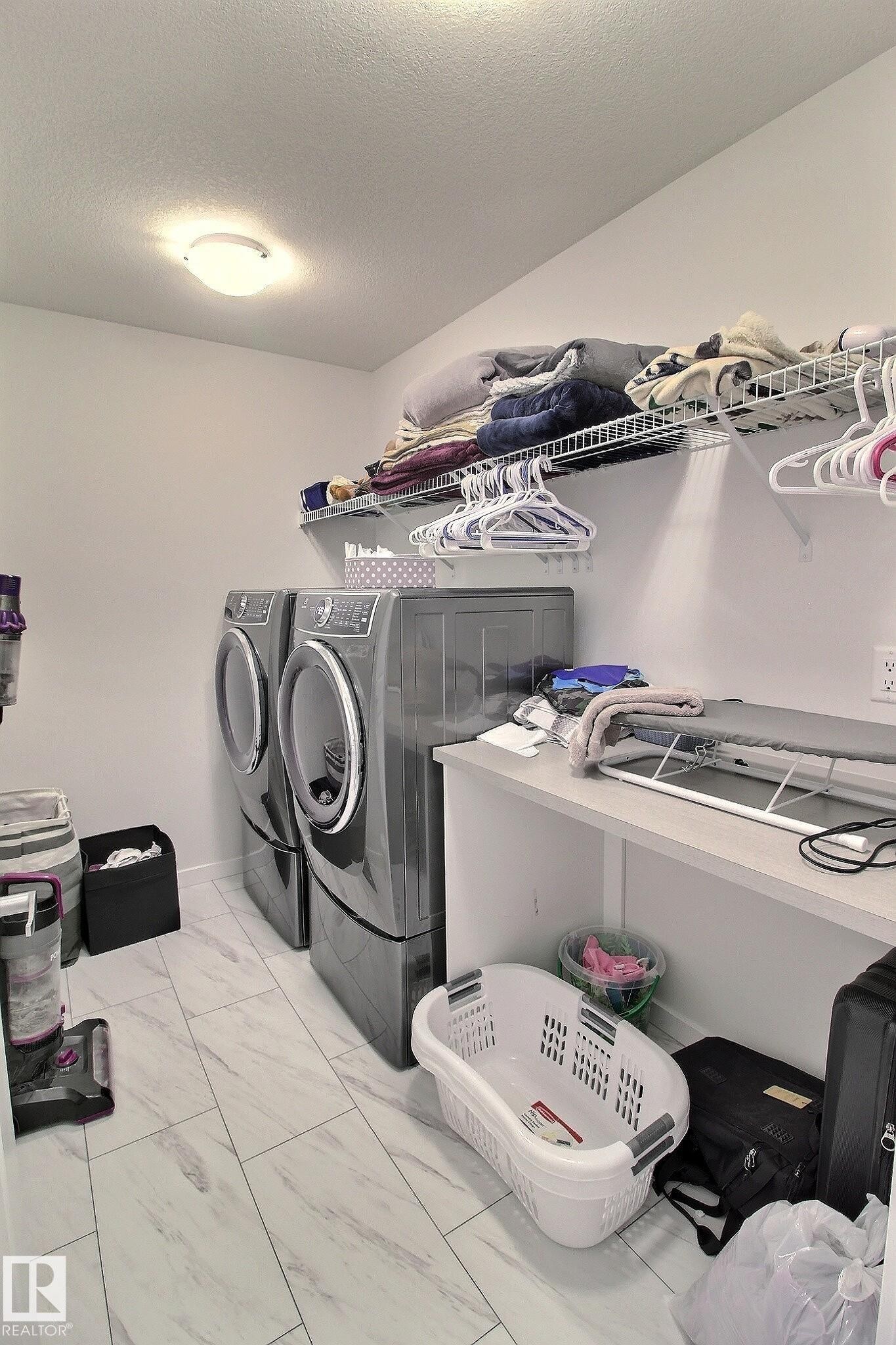 Utility room featuring light-toned flooring, built-in shelving, and a countertop - 121 Stiles Bend, Leduc, AB - Indoor Photo Showing Laundry Room