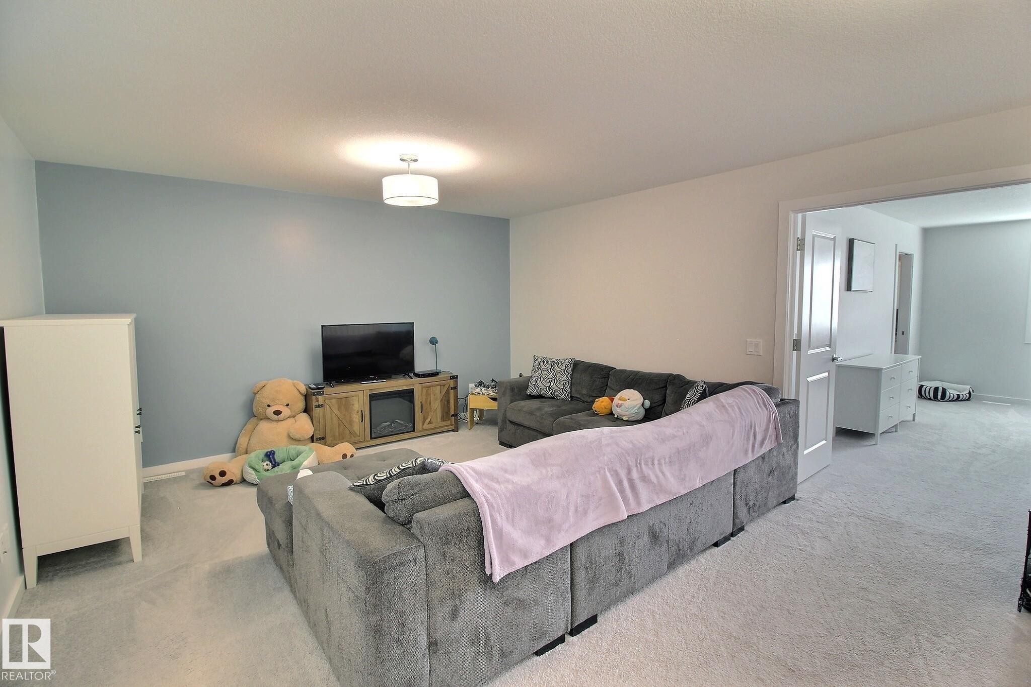 Spacious room featuring light blue accent wall and recessed lighting - 121 Stiles Bend, Leduc, AB - Indoor
