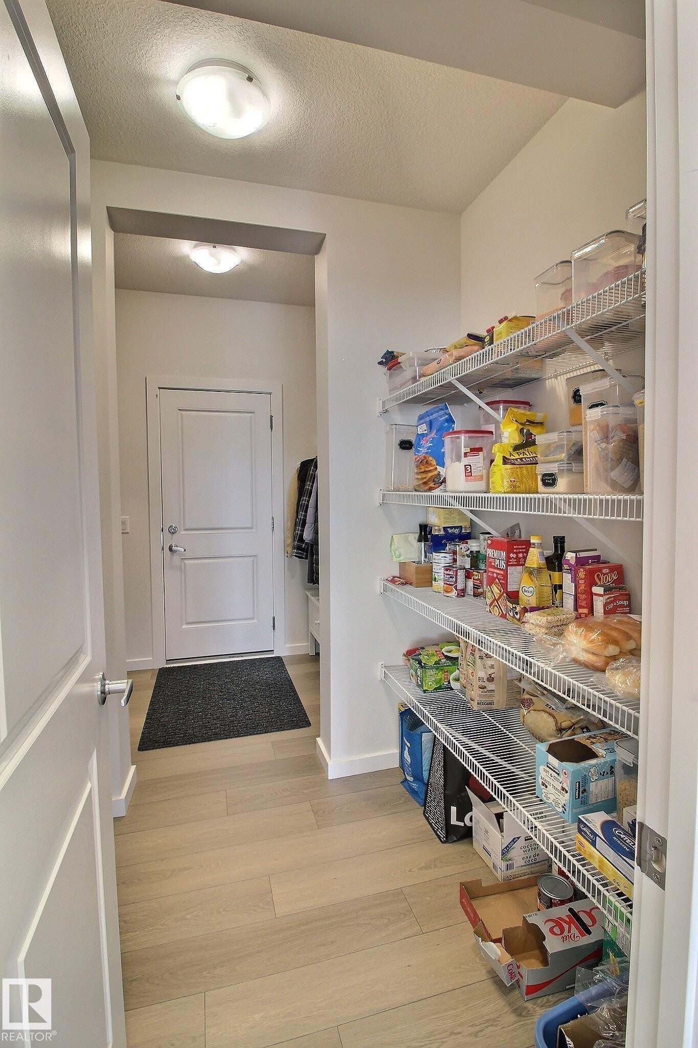 Kitchen pantry featuring multiple wire shelving units, light wood-finish flooring, and recessed lighting - 121 Stiles Bend, Leduc, AB - Indoor