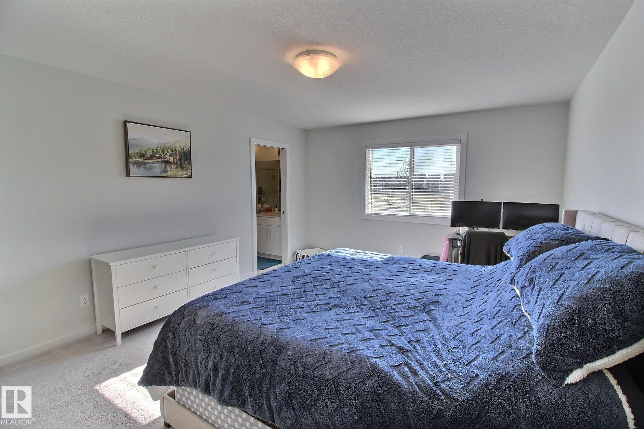 Carpeted room featuring a white-framed window with blinds, a recessed doorway, and a ceiling-mounted light fixture - 121 Stiles Bend, Leduc, AB - Indoor Photo Showing Bedroom