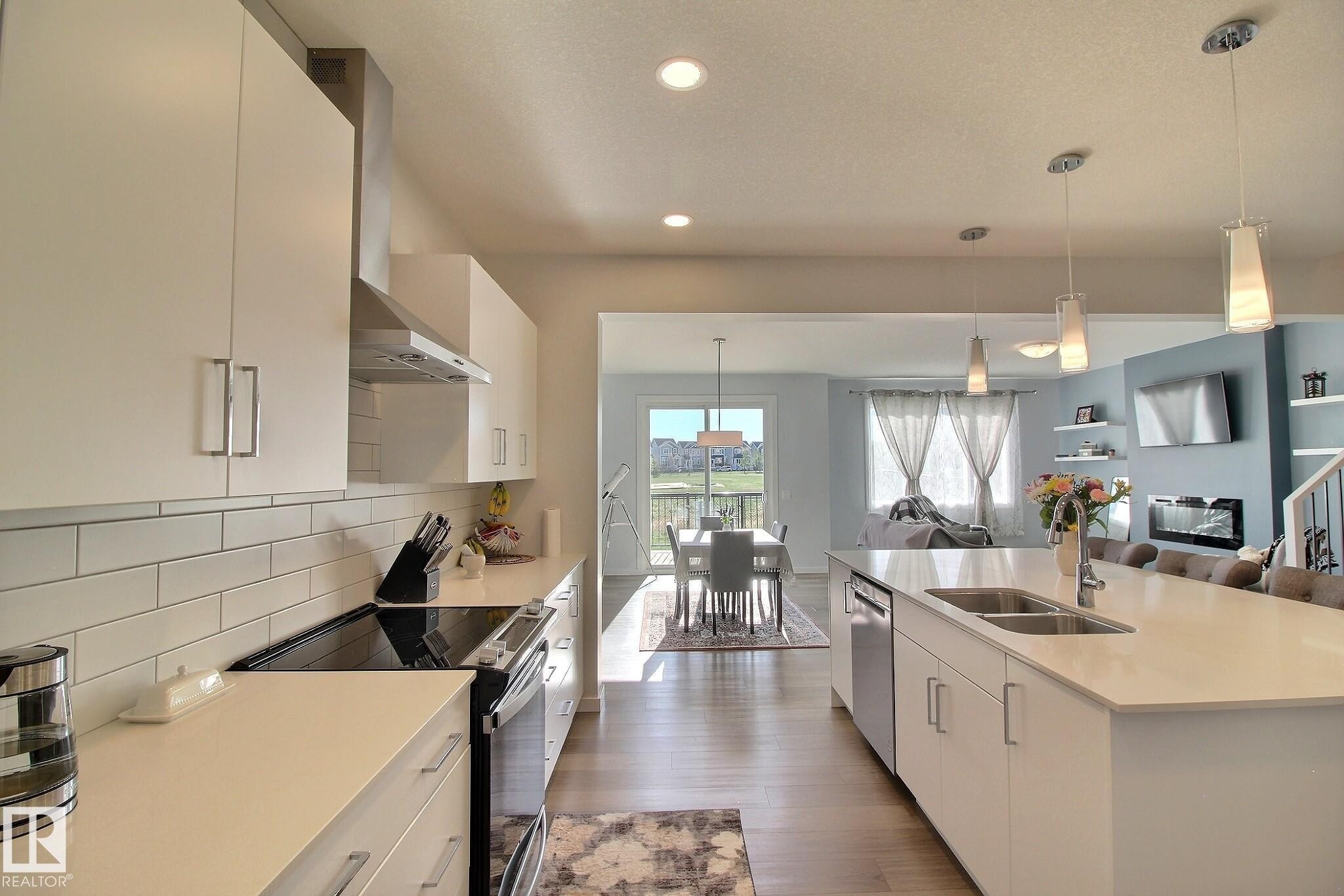 Bright kitchen featuring light-finish cabinetry, stainless steel appliances, and a subway tile backsplash - 121 Stiles Bend, Leduc, AB - Indoor Photo Showing Kitchen With Double Sink With Upgraded Kitchen