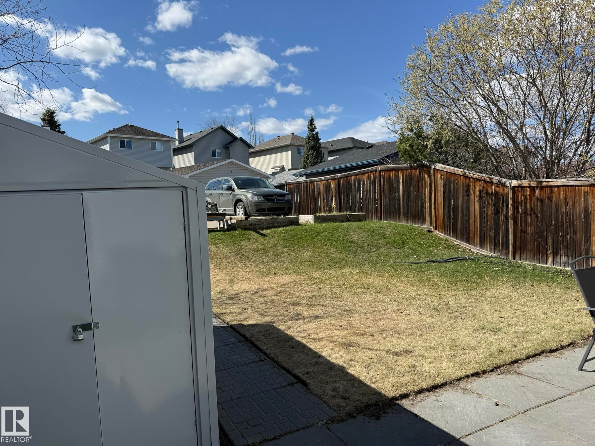 Expansive backyard featuring a partial patio, a storage shed, and a privacy fence - 645 Windross Crescent, Edmonton, AB