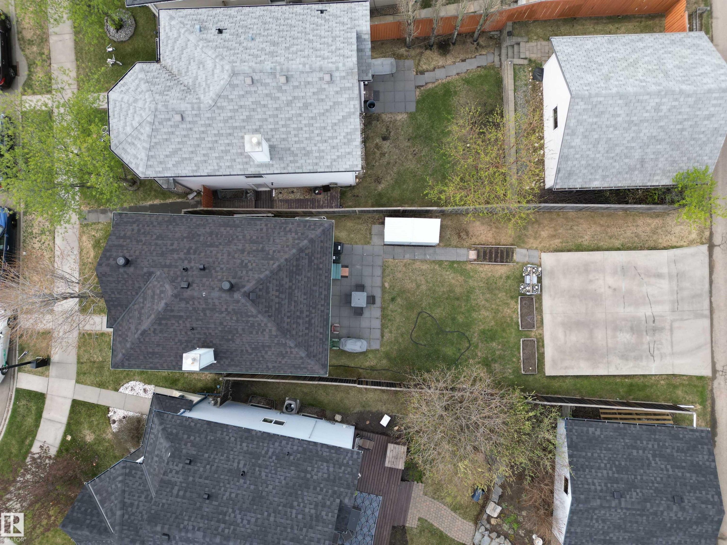 Aerial perspective showcasing a property with a dark shingle roof, a paved patio area, and a large concrete pad - 645 Windross Crescent, Edmonton, AB