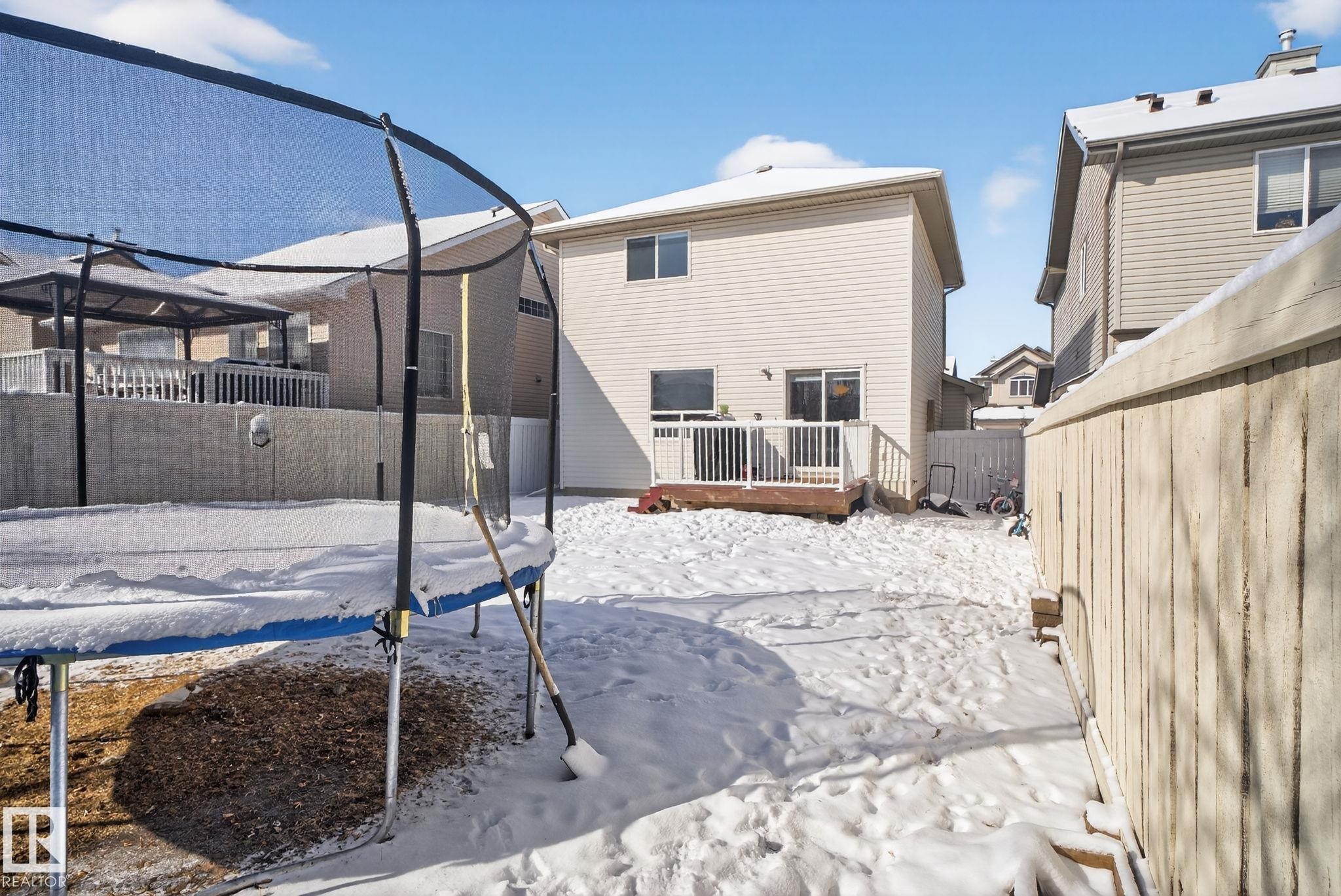 Rear exterior featuring a wood deck with white railing, light-colored siding, and a sliding glass door - 421 84 Street, Edmonton, AB - Outdoor With Deck Patio Veranda With Exterior
