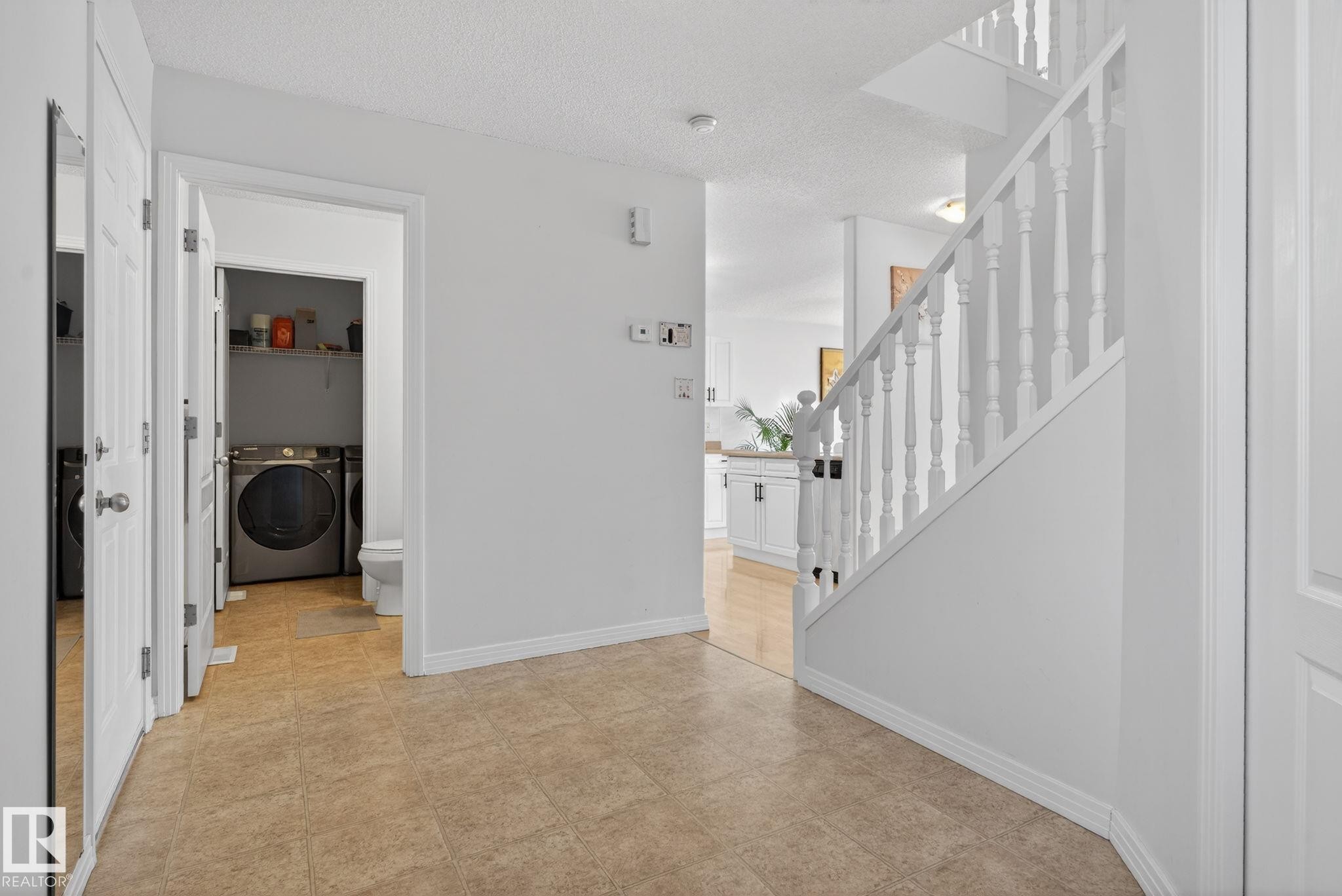 Entryway featuring tiled flooring, white painted walls, and a white staircase with spindle balusters - 421 84 Street, Edmonton, AB - Indoor Photo Showing Other Room