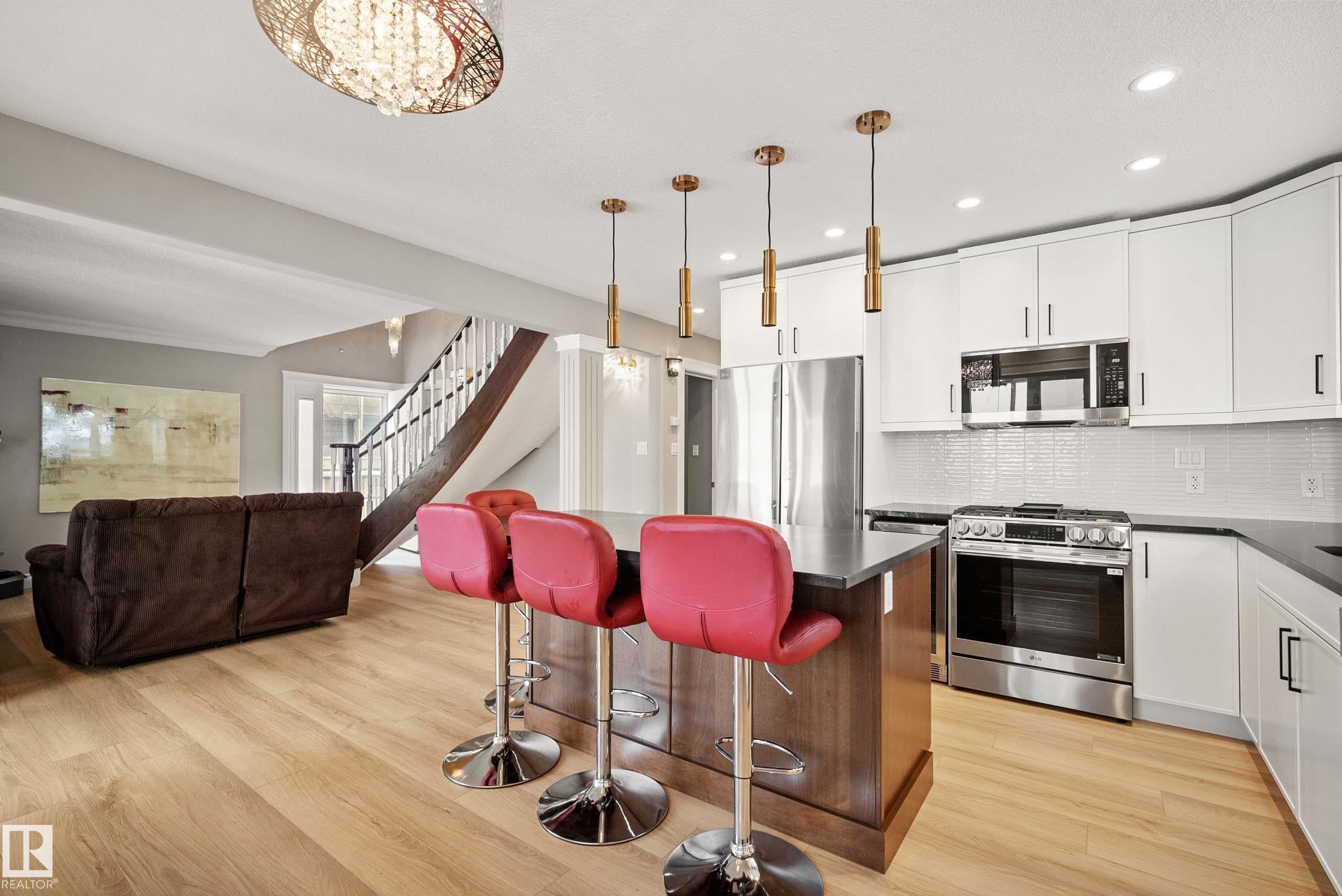 Modern kitchen featuring white cabinetry, stainless steel appliances, dark countertops, and a central island with pendant lighting - 104 Bayview Drive, Rural Parkland County, AB - Indoor Photo Showing Kitchen With Upgraded Kitchen