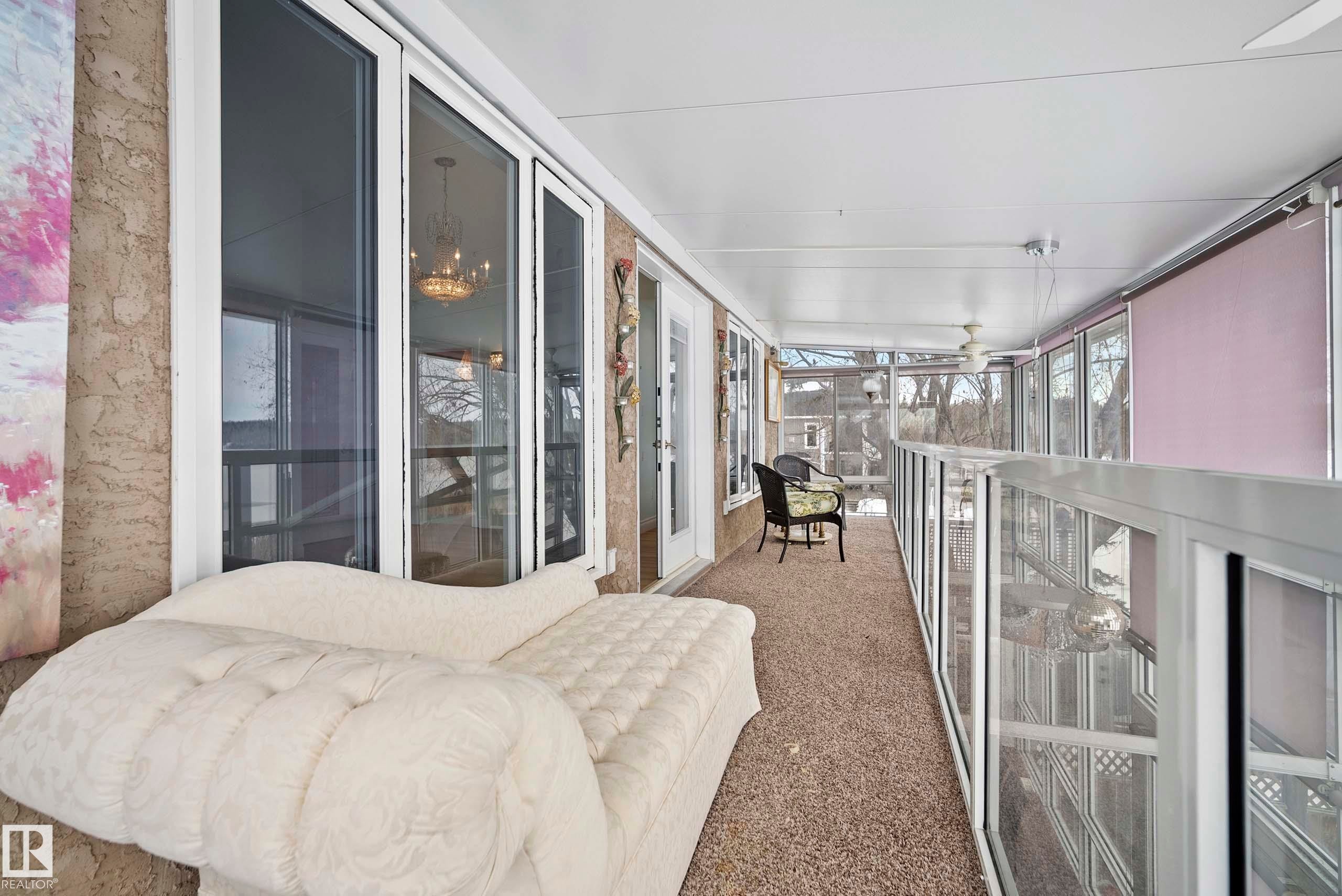 Enclosed upper-level balcony featuring full-height windows, a glass-paneled railing, and a textured ceiling with ceiling fans - 104 Bayview Drive, Rural Parkland County, AB - Indoor Photo Showing Other Room