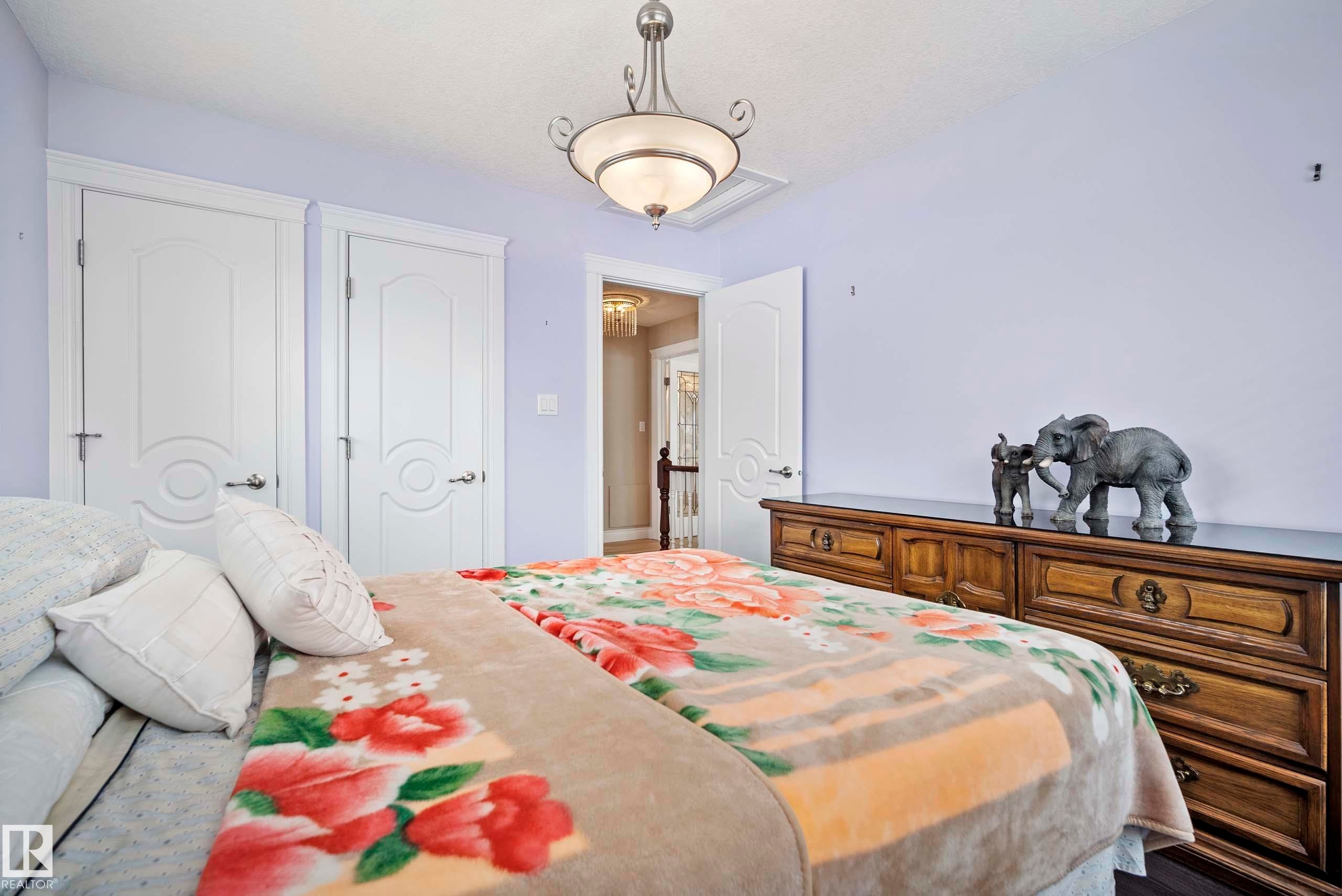 Chamber featuring two white panel doors, a hallway entrance, and a traditional ceiling light fixture - 104 Bayview Drive, Rural Parkland County, AB - Indoor Photo Showing Bedroom
