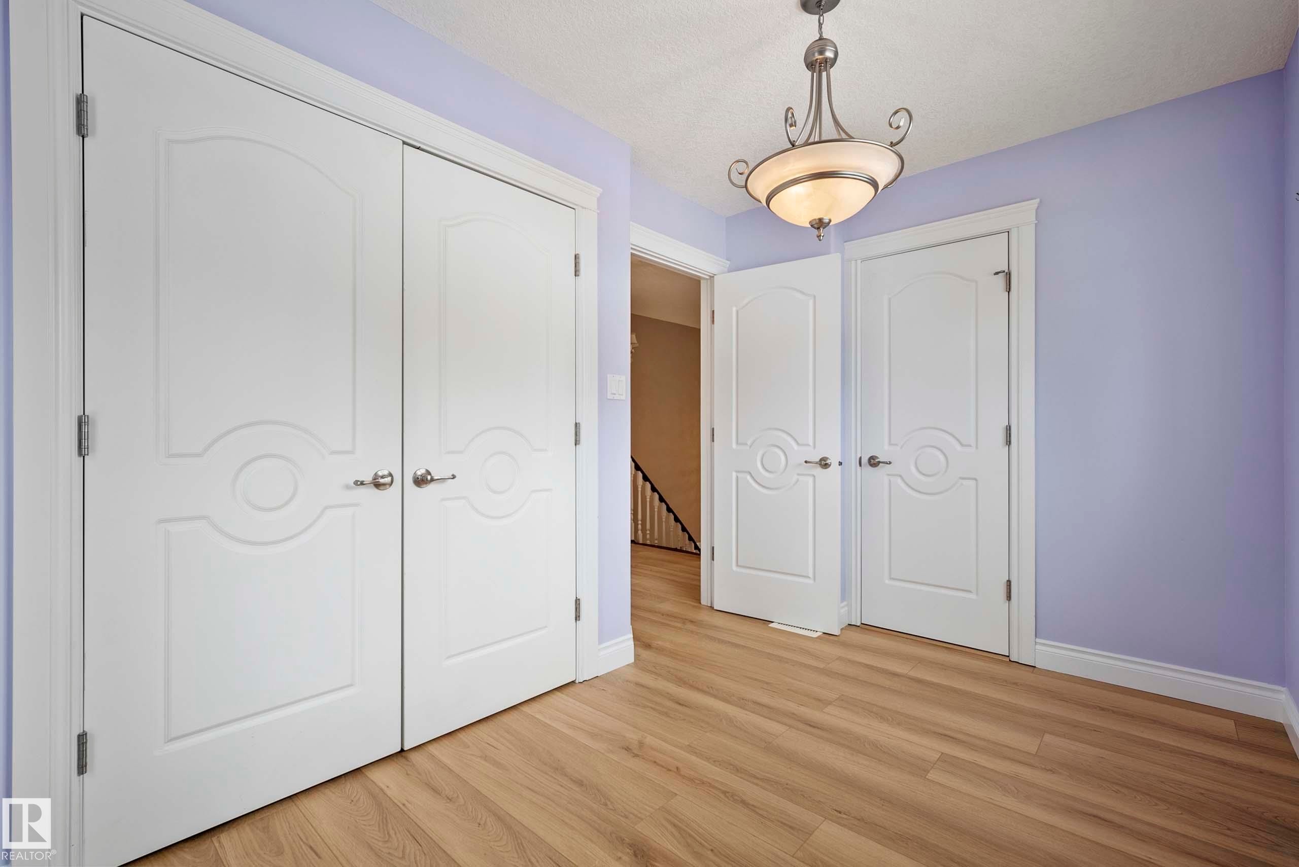Interior space featuring light wood-finish flooring, white baseboards, and a decorative semi-flush mount light fixture - 104 Bayview Drive, Rural Parkland County, AB - Indoor Photo Showing Other Room