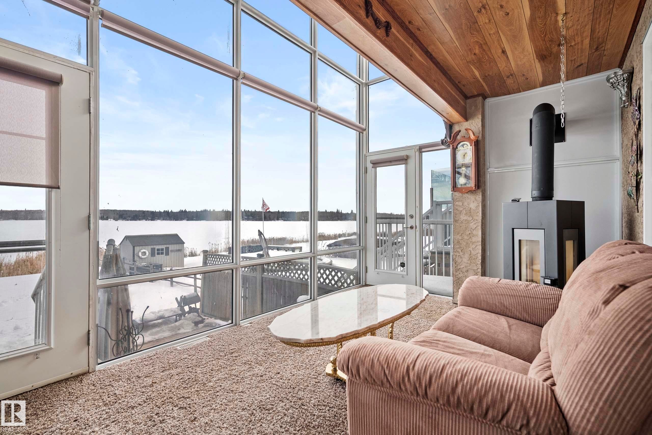Expansive sunroom featuring full-height windows, a wood-finish vaulted ceiling, and a modern freestanding fireplace - 104 Bayview Drive, Rural Parkland County, AB - Photo Showing Other Room