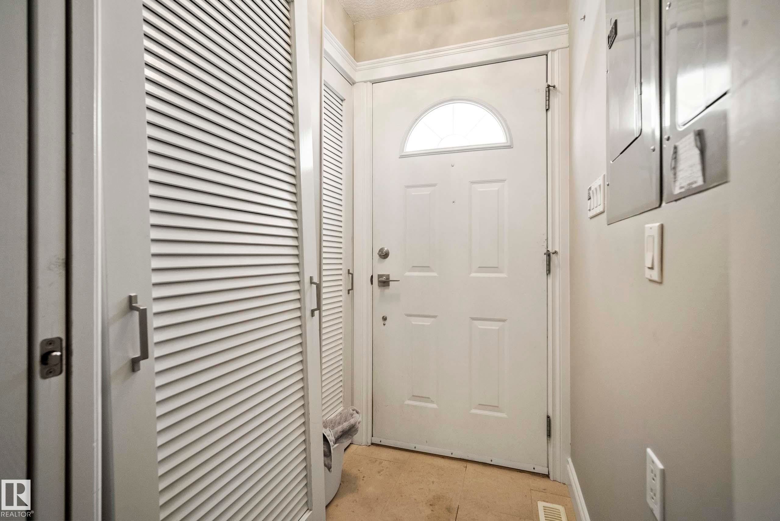 Entryway featuring a white paneled door with an arched transom window, a louvered bi-fold closet door, and light-toned flooring - 104 Bayview Drive, Rural Parkland County, AB - Indoor Photo Showing Other Room