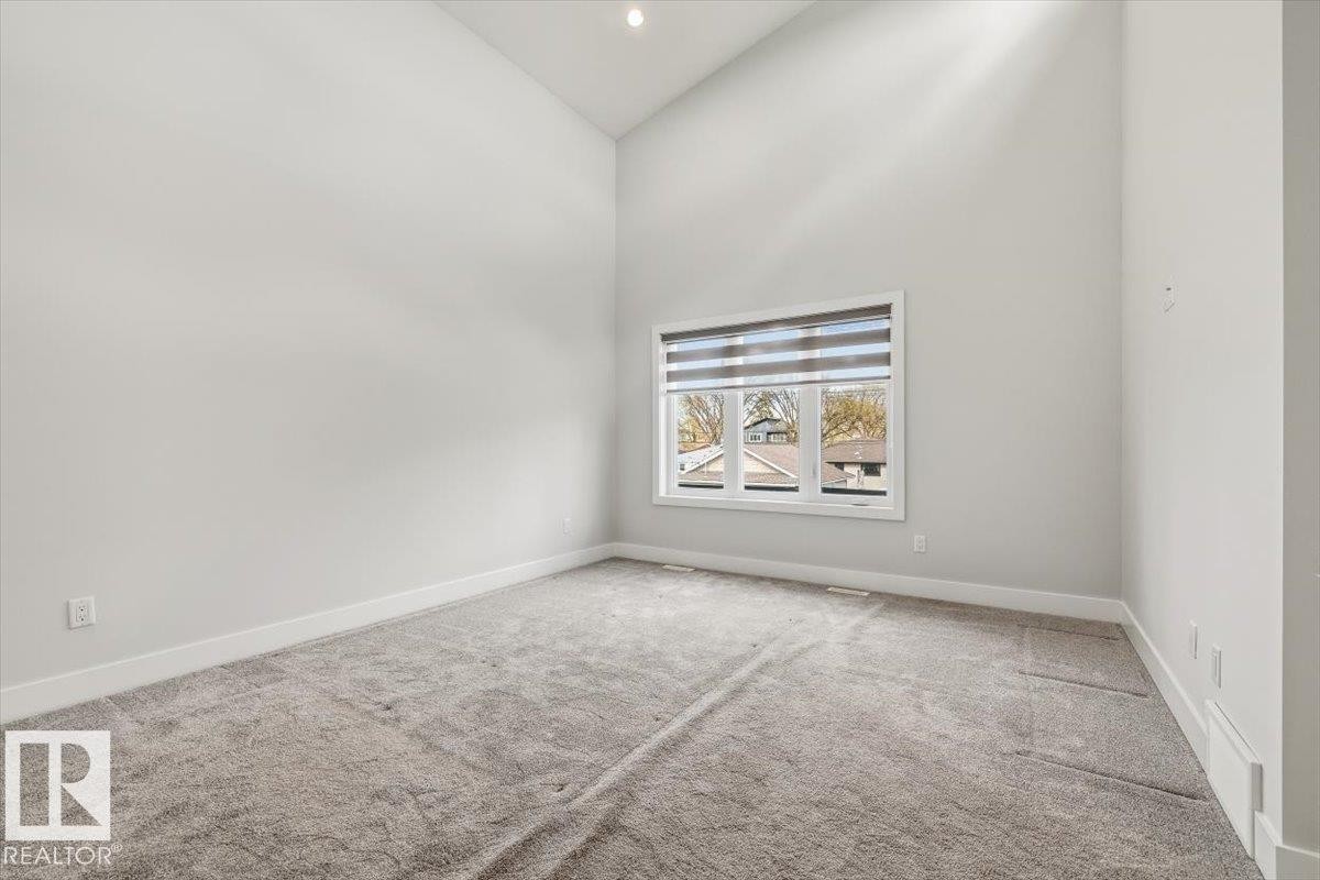 Spacious room featuring vaulted ceilings, plush grey carpeting, and a large window with privacy blinds - 9933 79 Street, Edmonton, AB - Indoor Photo Showing Other Room