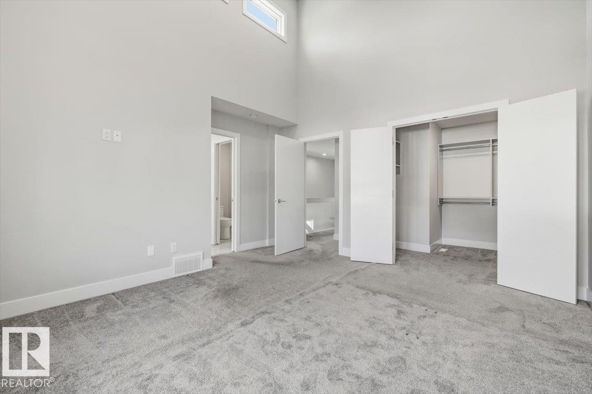 Spacious room featuring light gray carpeting, neutral wall finishes, and a high vaulted ceiling with an upper window - 9933 79 Street, Edmonton, AB - Indoor Photo Showing Other Room