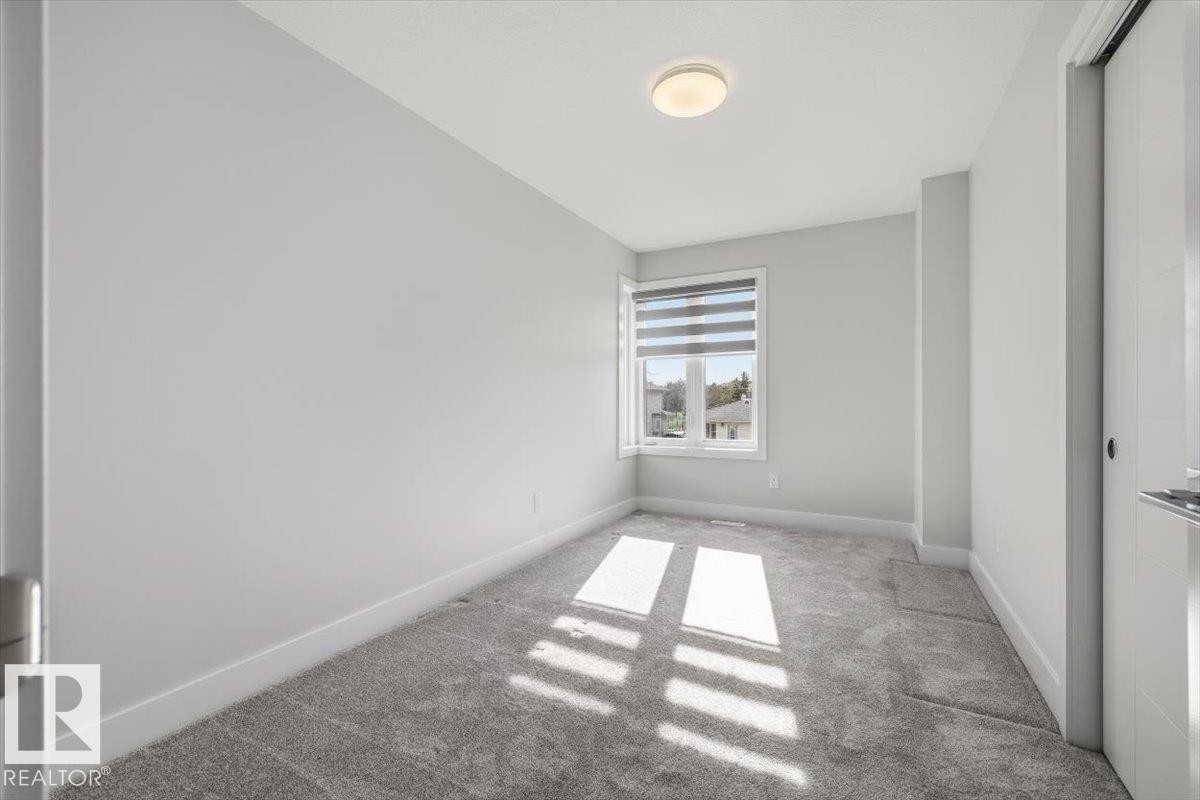 Neutral-toned room featuring a window with integrated blinds, grey carpet flooring, white baseboards, and a flush mount ceiling light fixture - 9933 79 Street, Edmonton, AB - Indoor Photo Showing Other Room