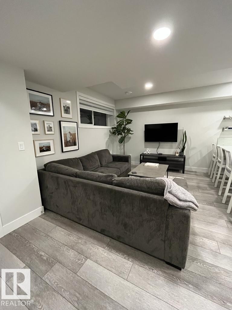 Well-lit living space featuring wood-finish flooring, recessed lighting, and a white baseboard trim - 9933 79 Street, Edmonton, AB - Indoor