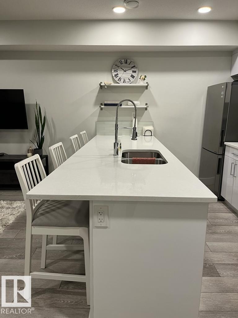 Kitchen island with an undermount sink, gooseneck faucet, and integrated seating - 9933 79 Street, Edmonton, AB - Indoor
