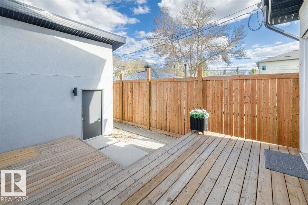 Expansive wood-finish deck with privacy fencing, a stucco exterior, and a built-in outdoor light fixture - 9933 79 Street, Edmonton, AB - Outdoor With Deck Patio Veranda With Exterior