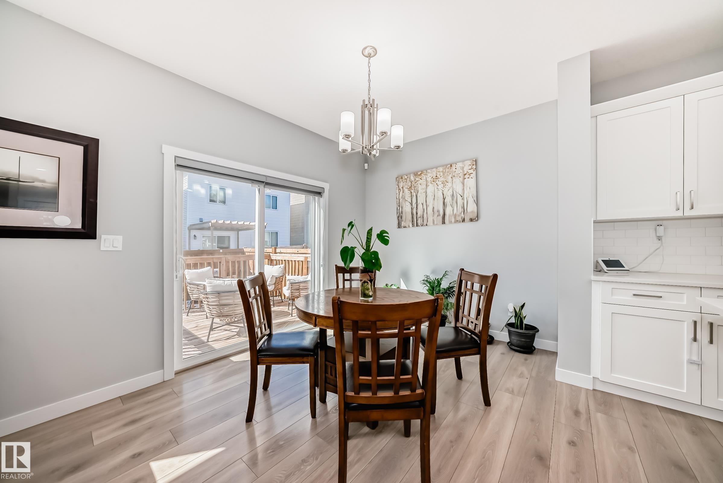Open-concept living area featuring light wood-finish flooring and a contemporary chandelier - 19635 29 Avenue, Edmonton, AB - Indoor Photo Showing Dining Room