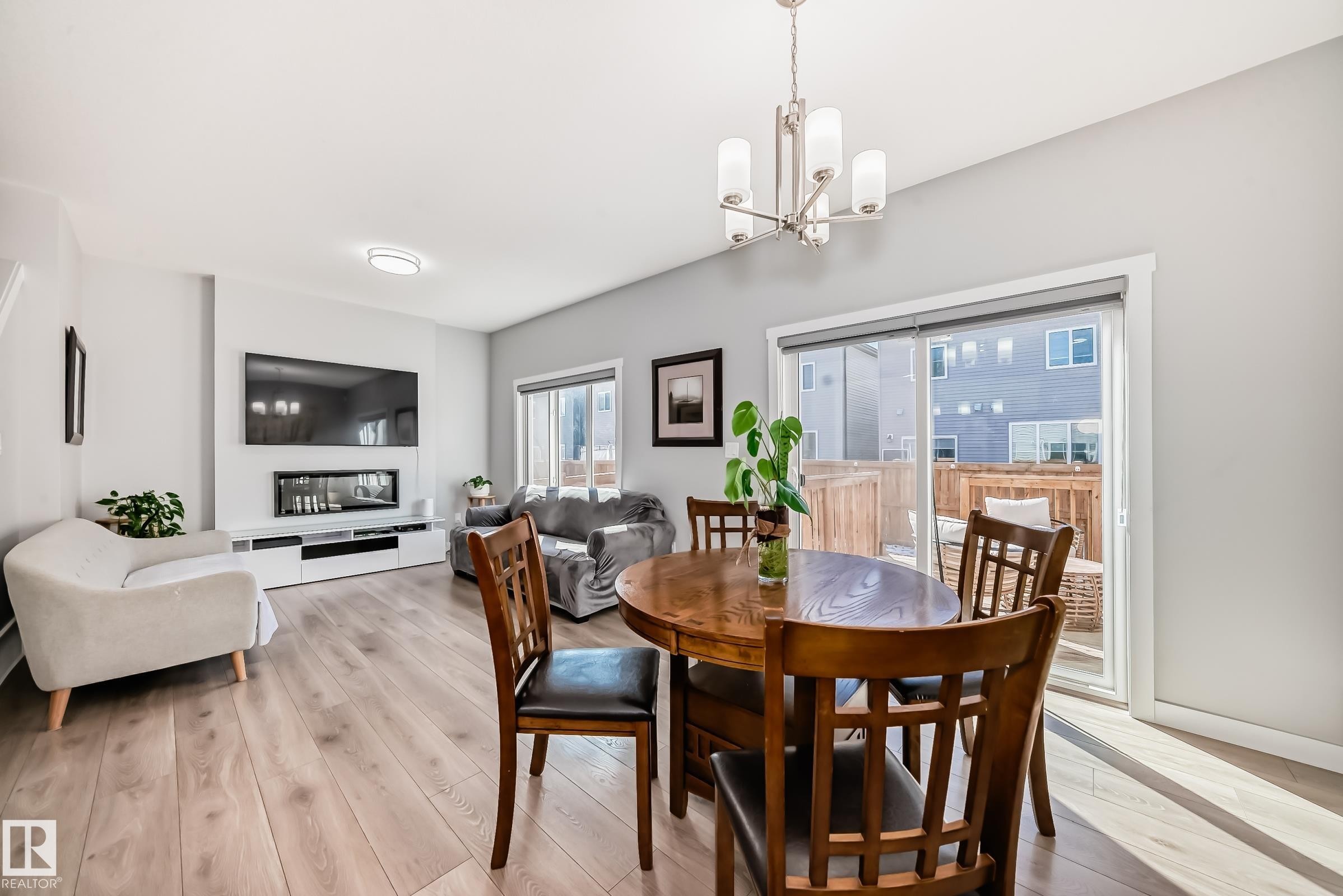 Open-concept living area with light wood-finish flooring, a contemporary linear fireplace, and a wall-mounted media console - 19635 29 Avenue, Edmonton, AB - Indoor