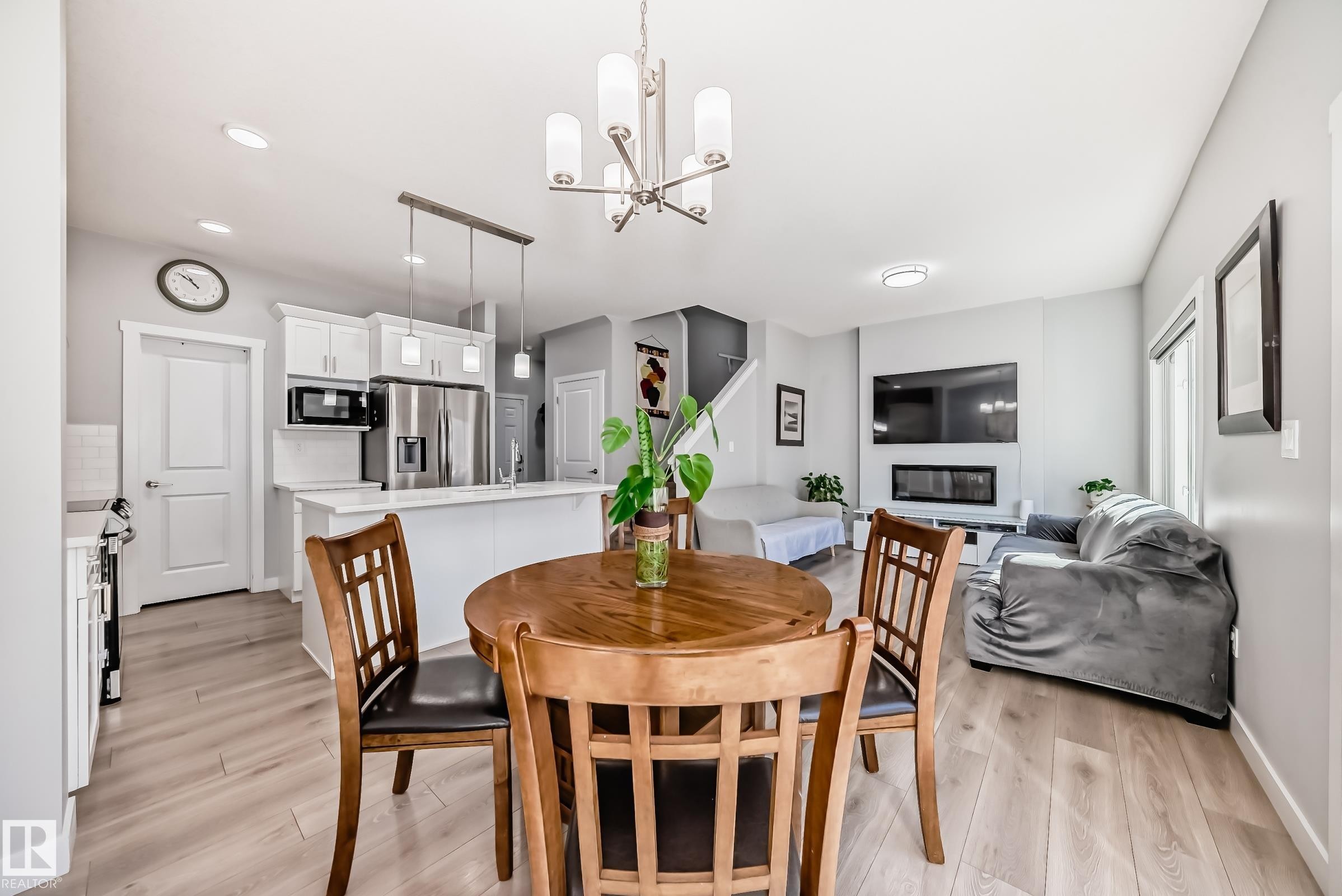 Open-concept living space featuring wood-finish flooring, a contemporary linear fireplace, and modern light fixtures - 19635 29 Avenue, Edmonton, AB - Indoor Photo Showing Dining Room